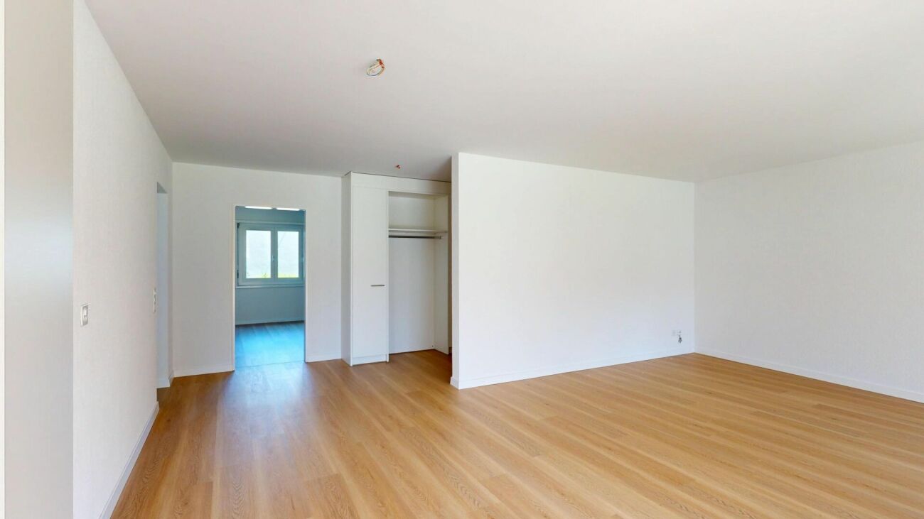 Leerer heller Wohnraum mit Parkett und Einbauschrank