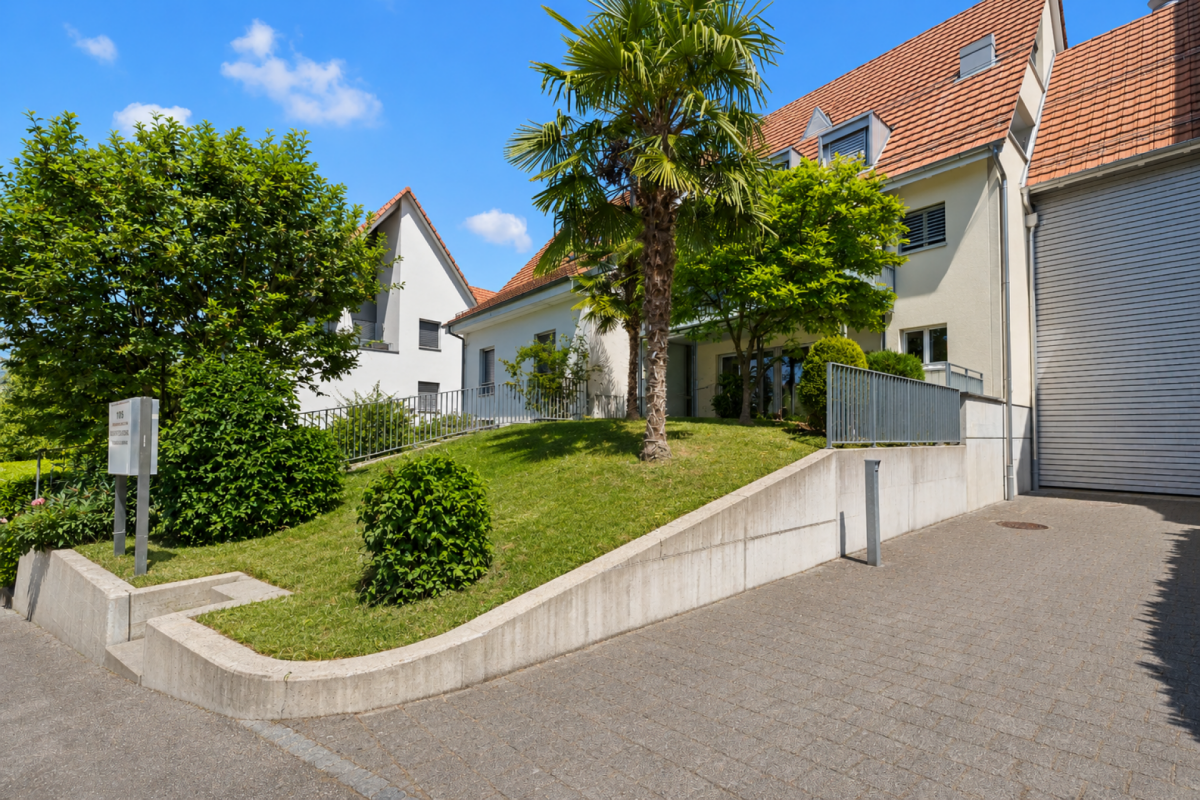 Außenansicht eines modernen Wohngebäudes mit Garten und Einfahrt