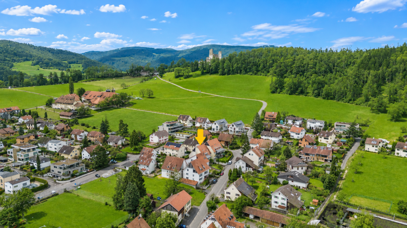 Luftaufnahme eines ländlichen Wohngebiets mit grünen Wiesen und Hügeln