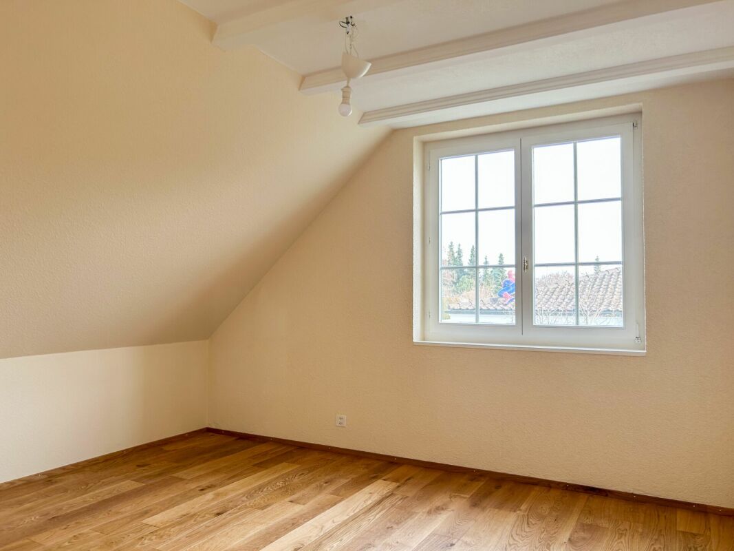 Dachzimmer mit Fenster und Holzboden