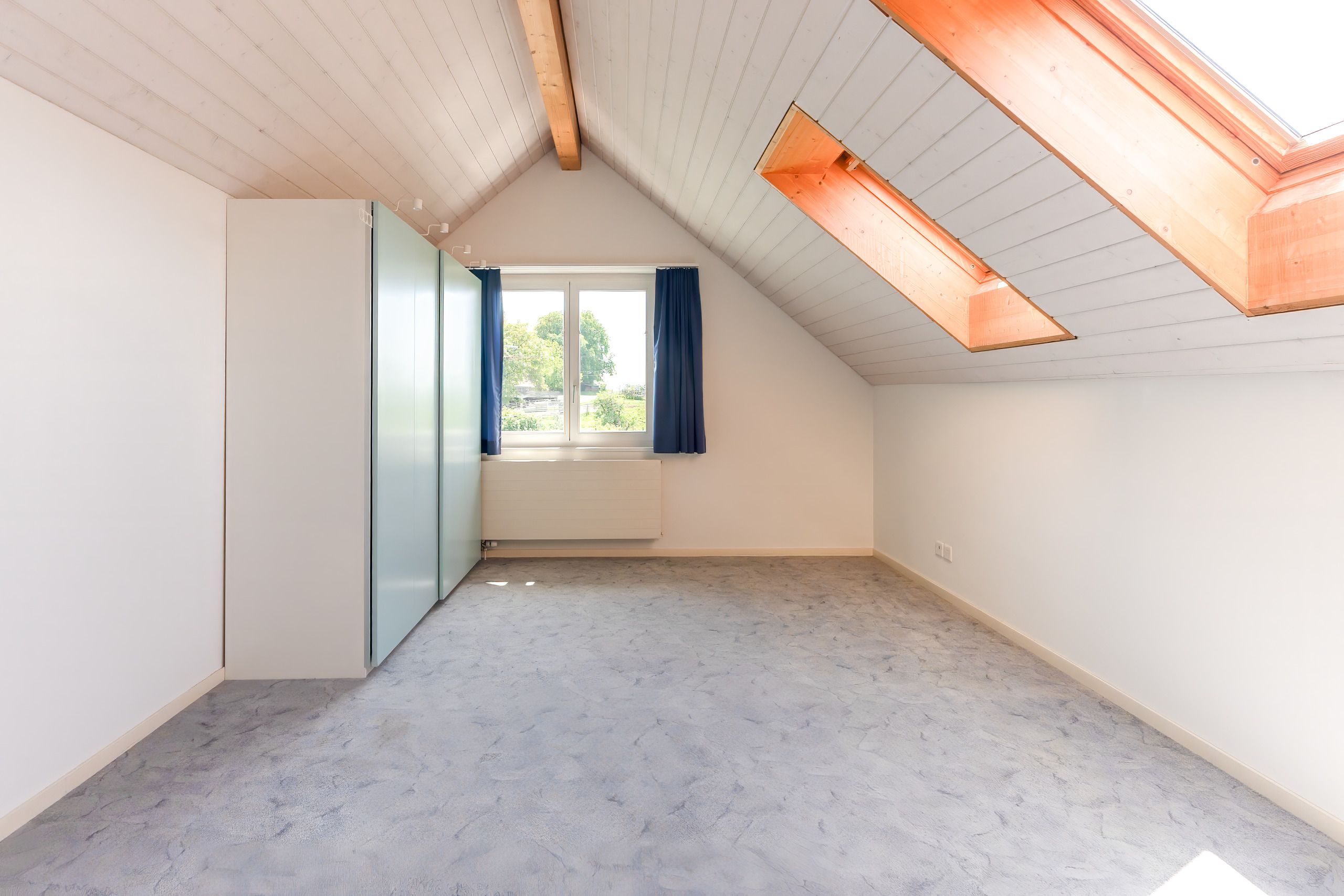 Ausgebautes Dachzimmer mit Fenster und Dachflächenfenstern