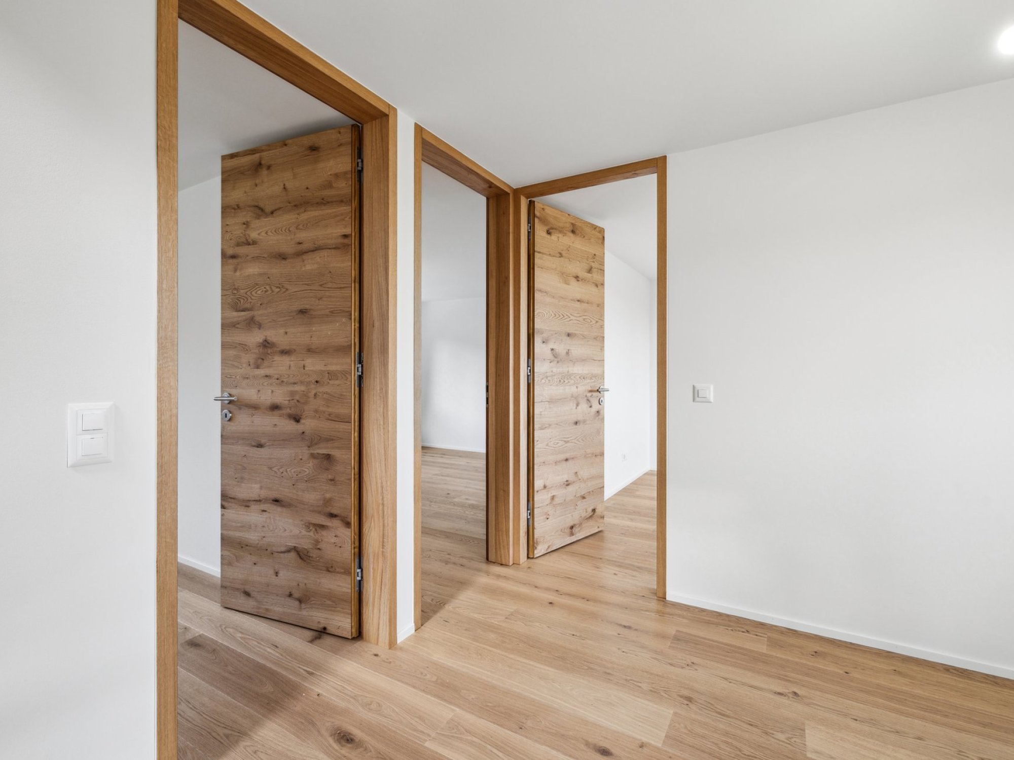 Heller Flur mit Holztüren und Eichenboden