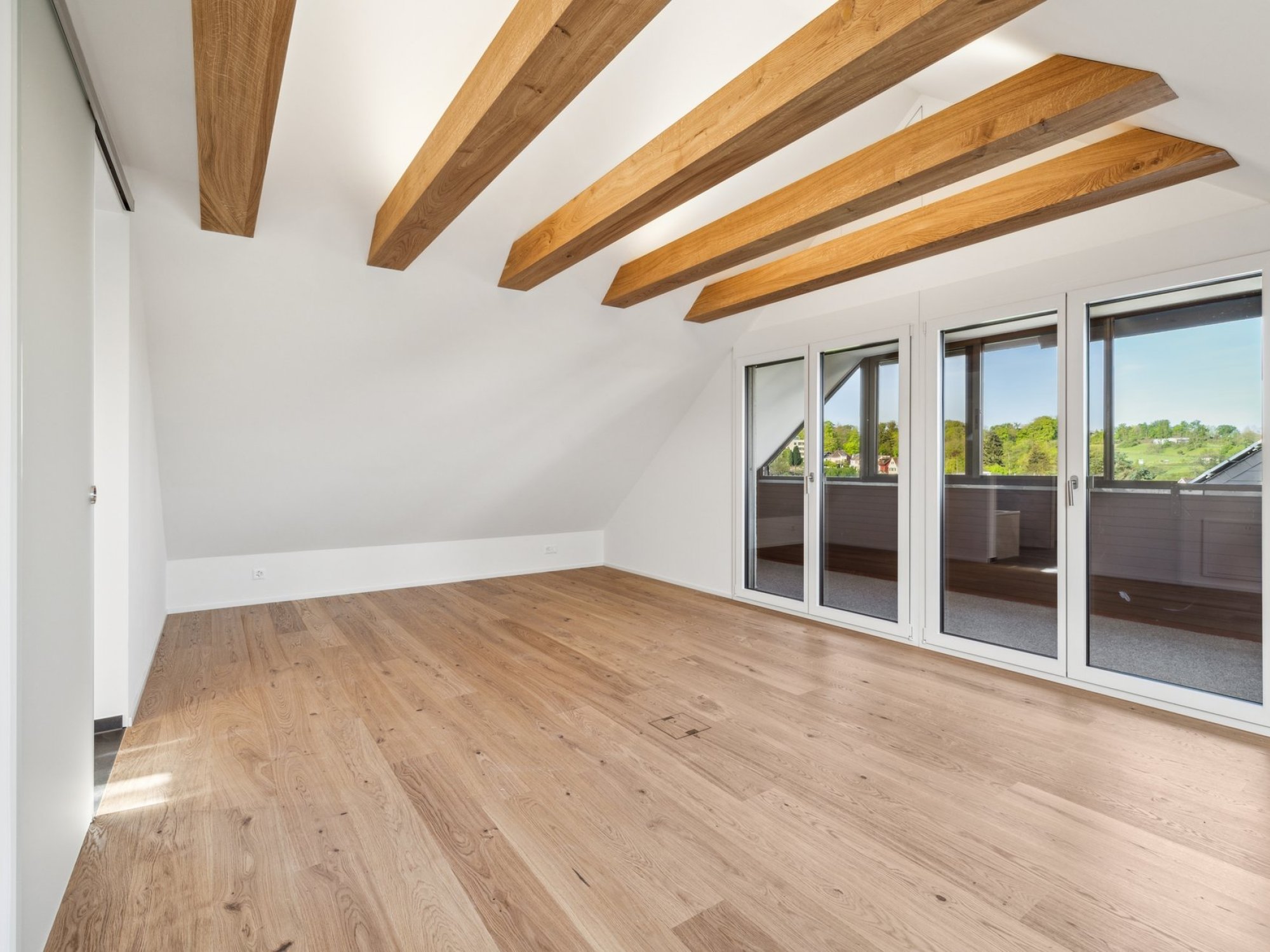 Heller leerer Dachraum mit Holzbalkendecke und Balkonblick