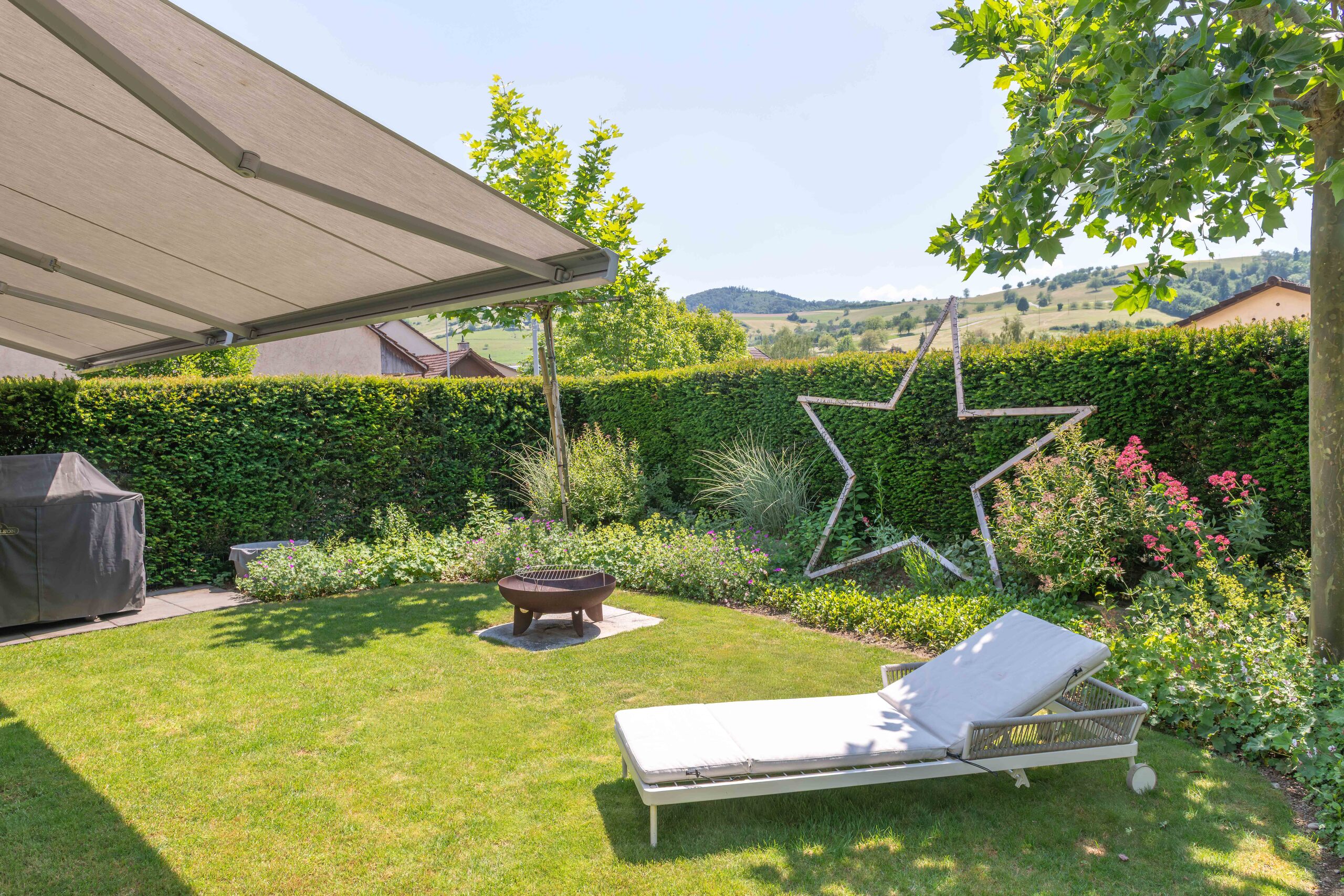 Gemütlicher Garten mit Sonnenliege und Feuerstelle