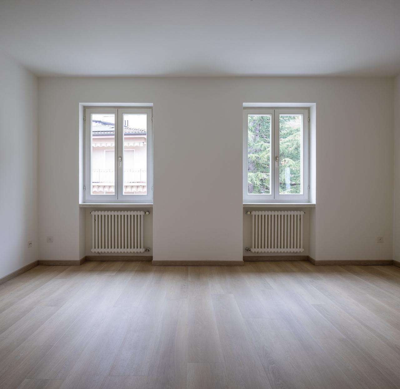 Leerer heller Raum mit zwei Fenstern und Heizkörpern