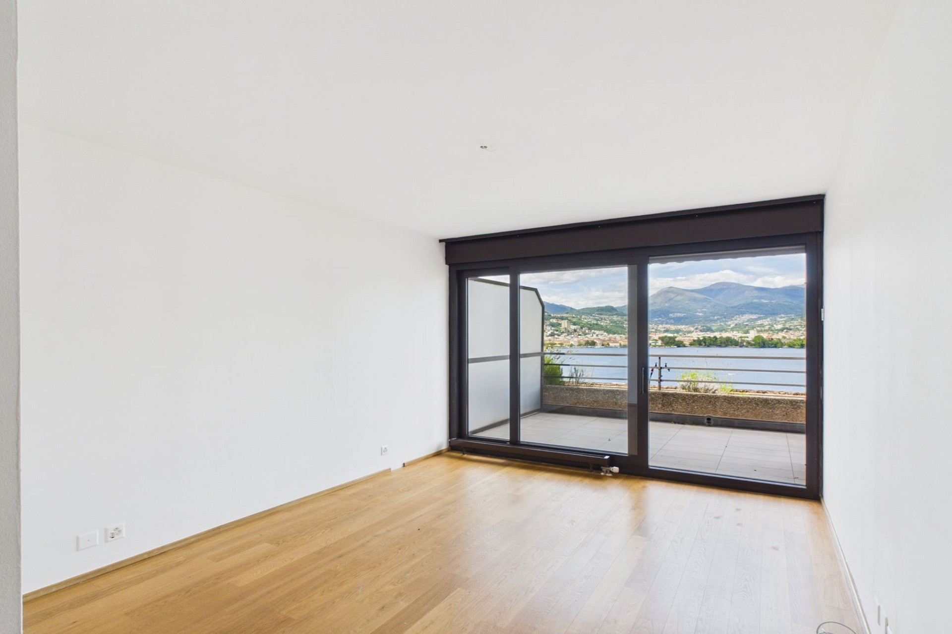 Leerer Wohnraum mit Balkon- und Seeblick