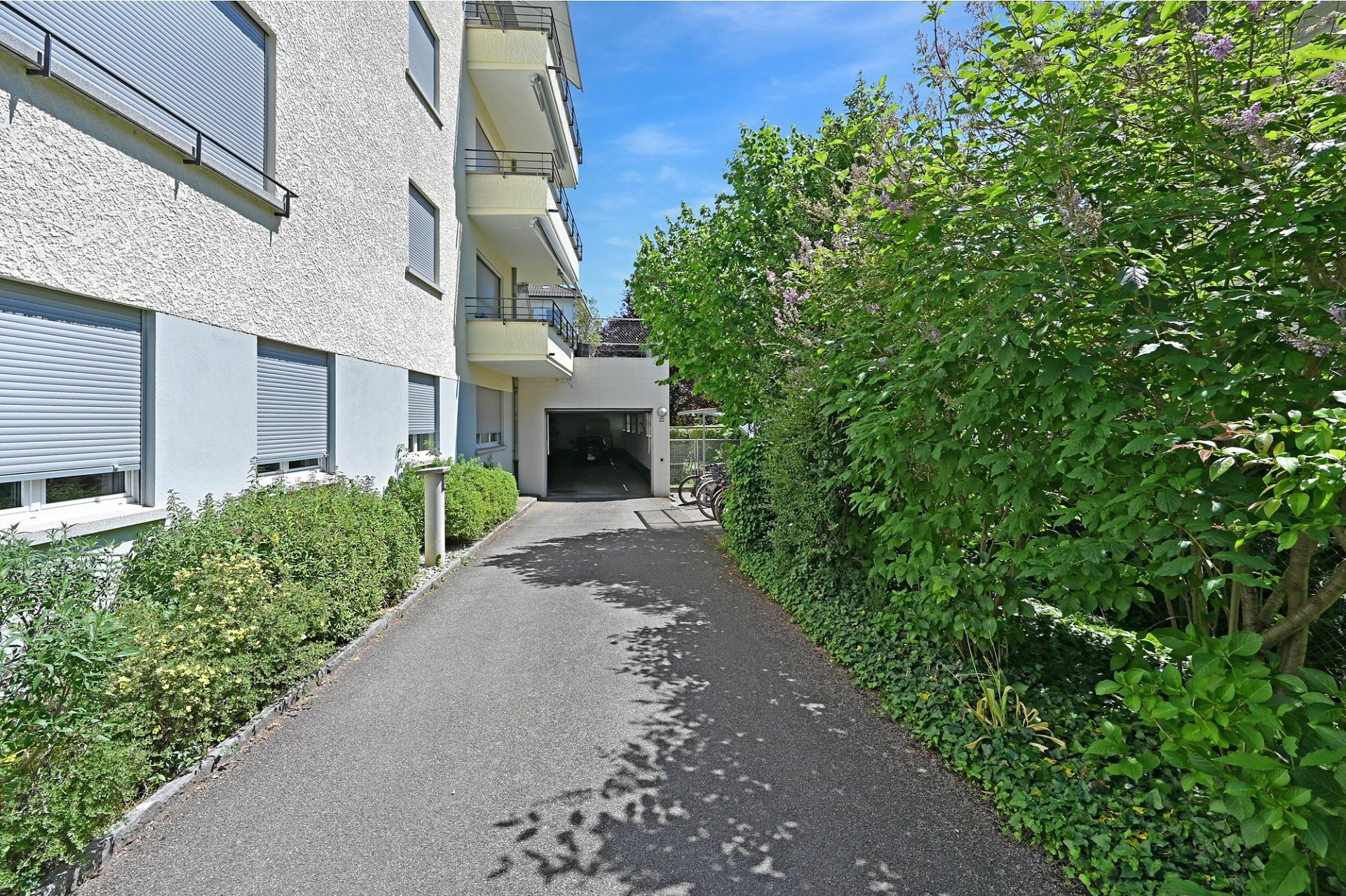 Wohnhauszufahrt mit Garage und Balkonfassade
