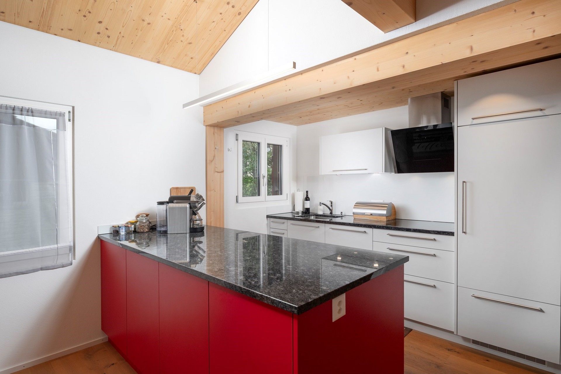 Moderne Küche mit Holzdecke und roter Kochinsel