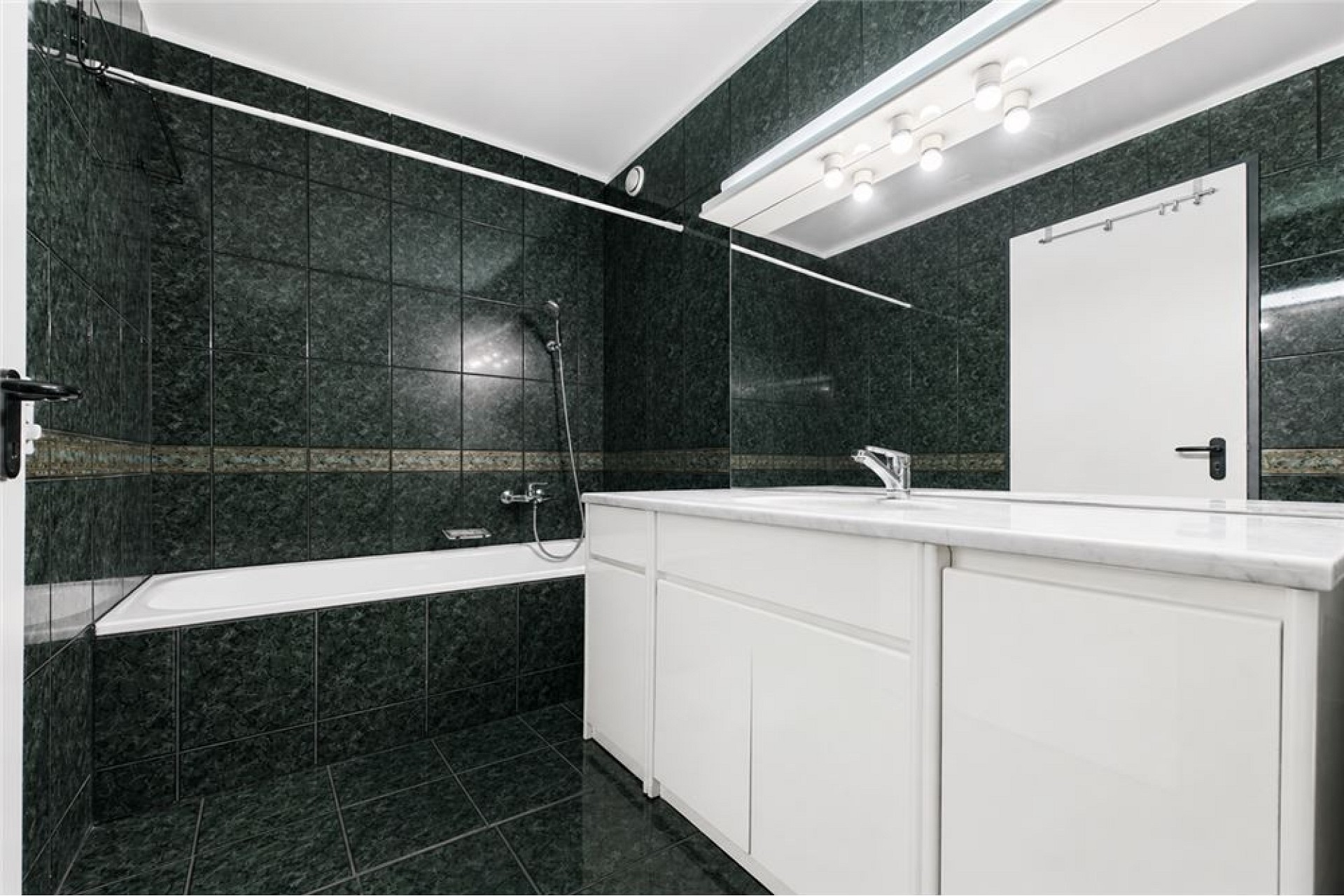 Modernes Badezimmer mit dunklen Fliesen und weißem Waschtisch