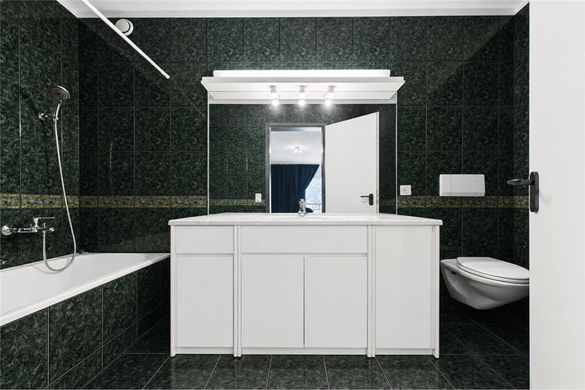 Modernes Badezimmer mit dunkler Fliesenverkleidung und weißem Waschtisch
