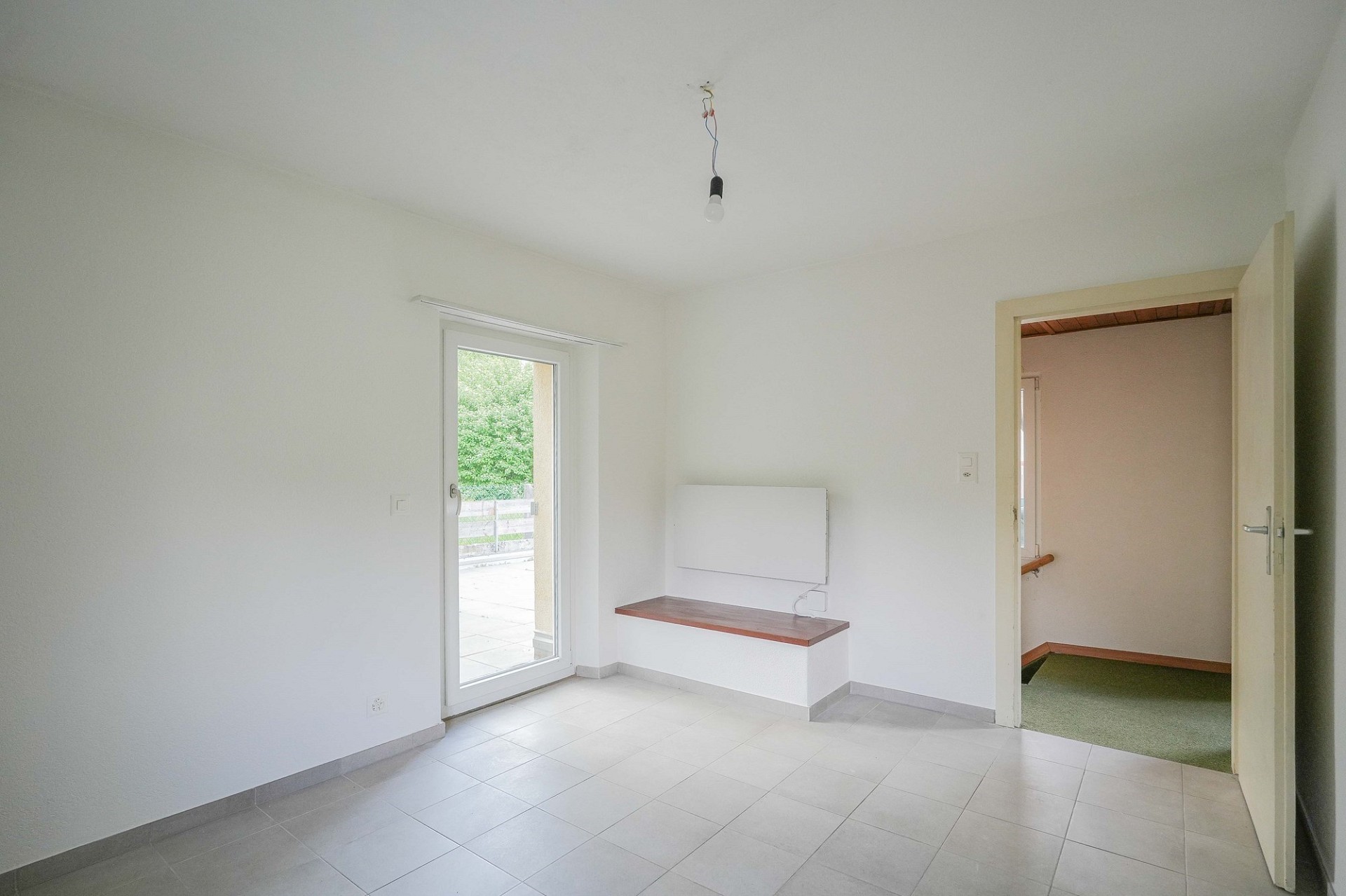 Leerer, heller Raum mit Fliesenboden und Fenster zur Terrasse