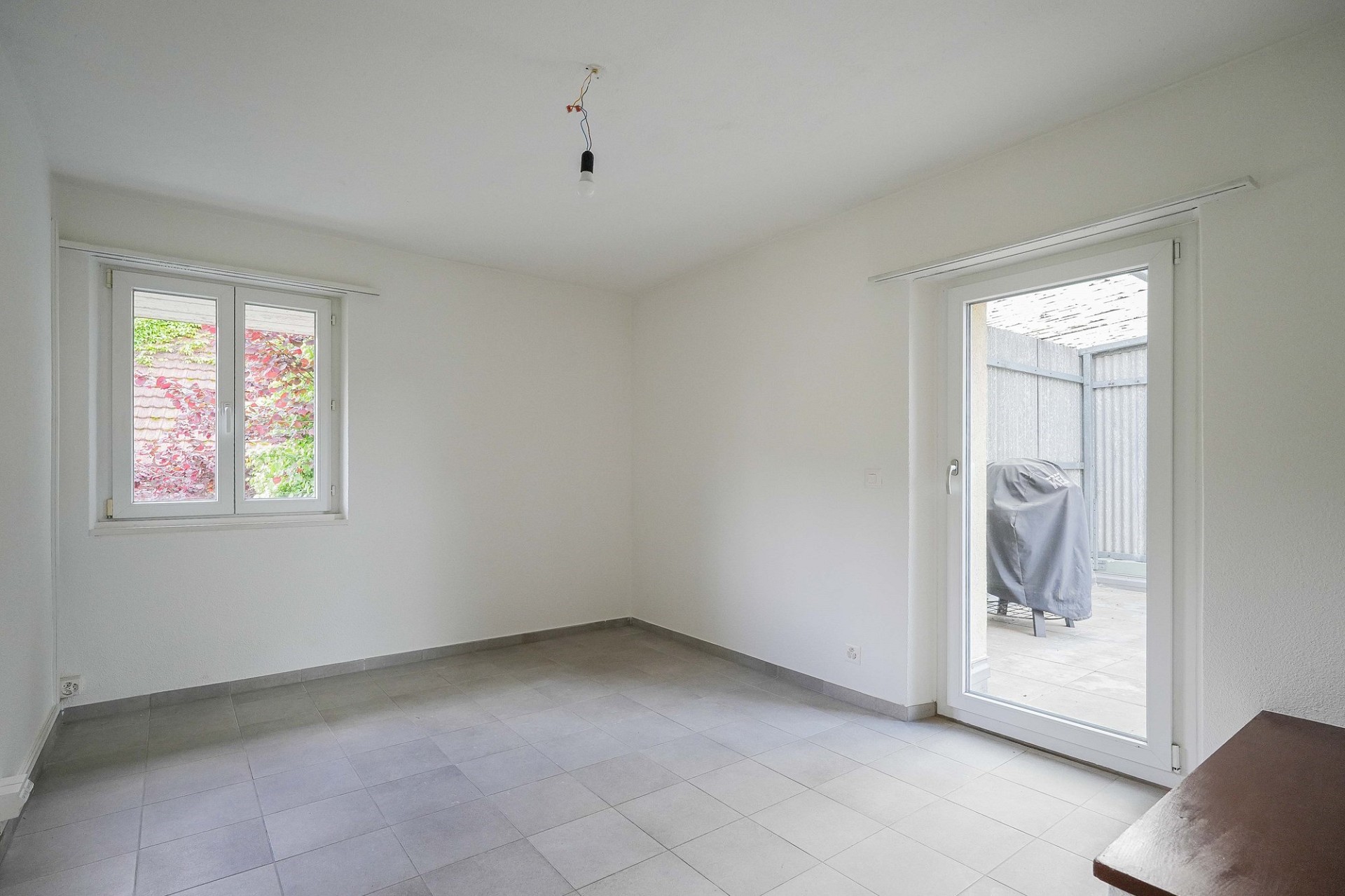 Heller leerer Raum mit Terrassentür und Fenster