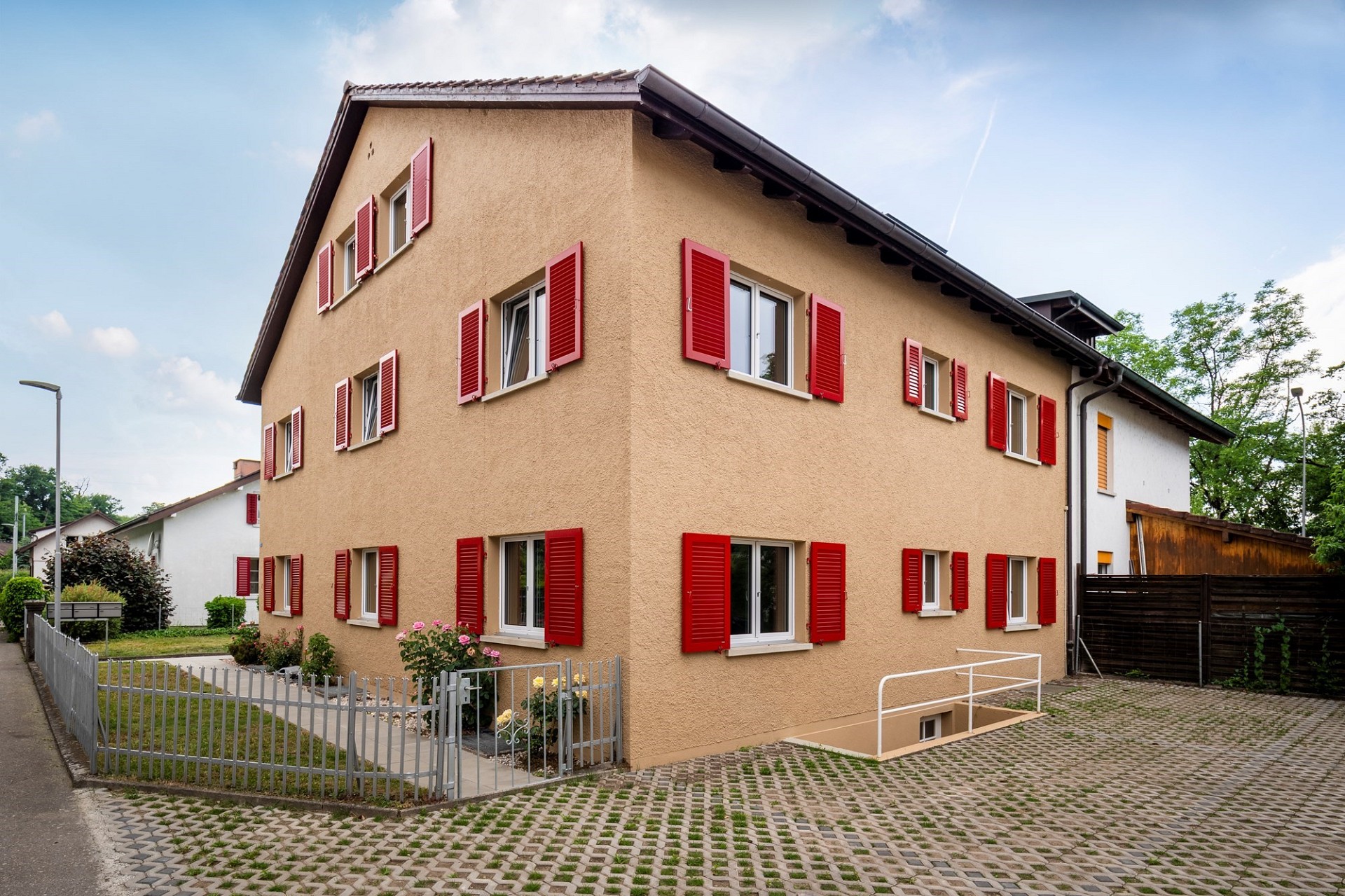 Außenansicht eines Wohnhauses mit roten Fensterläden