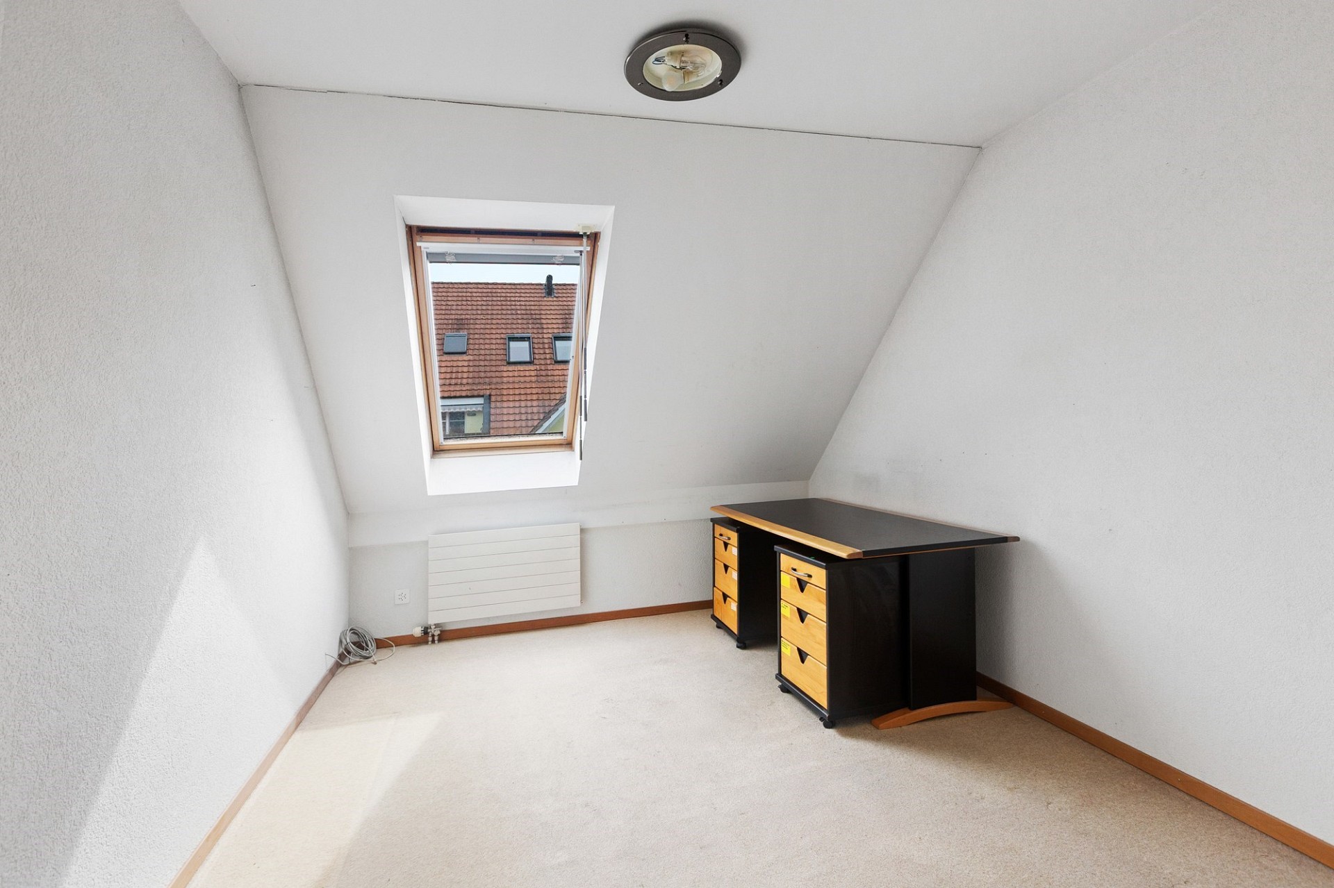 Dachzimmer mit Dachfenster und Schreibtisch