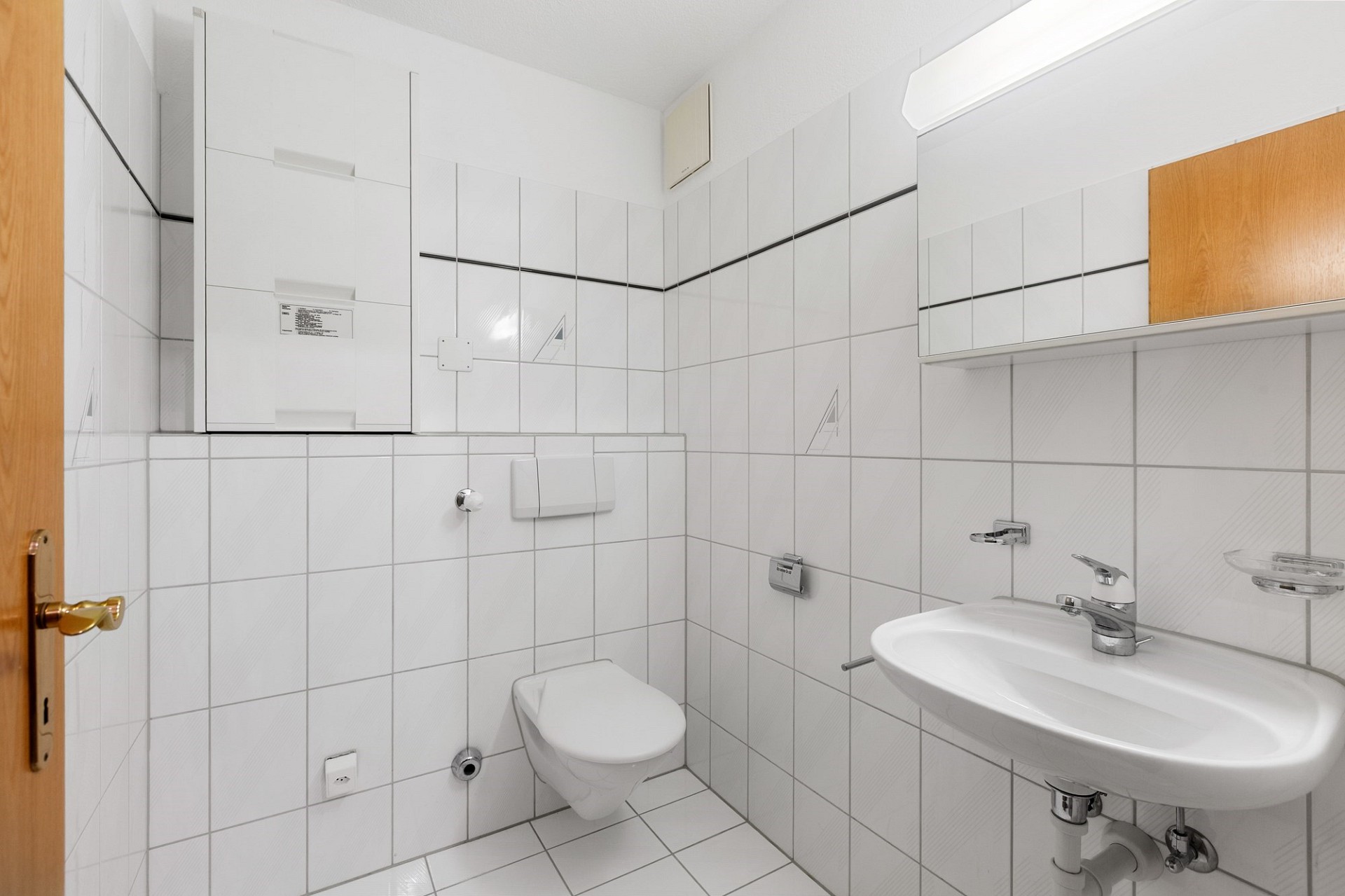 Kleines Gäste-WC mit weißen Fliesen und Waschtisch