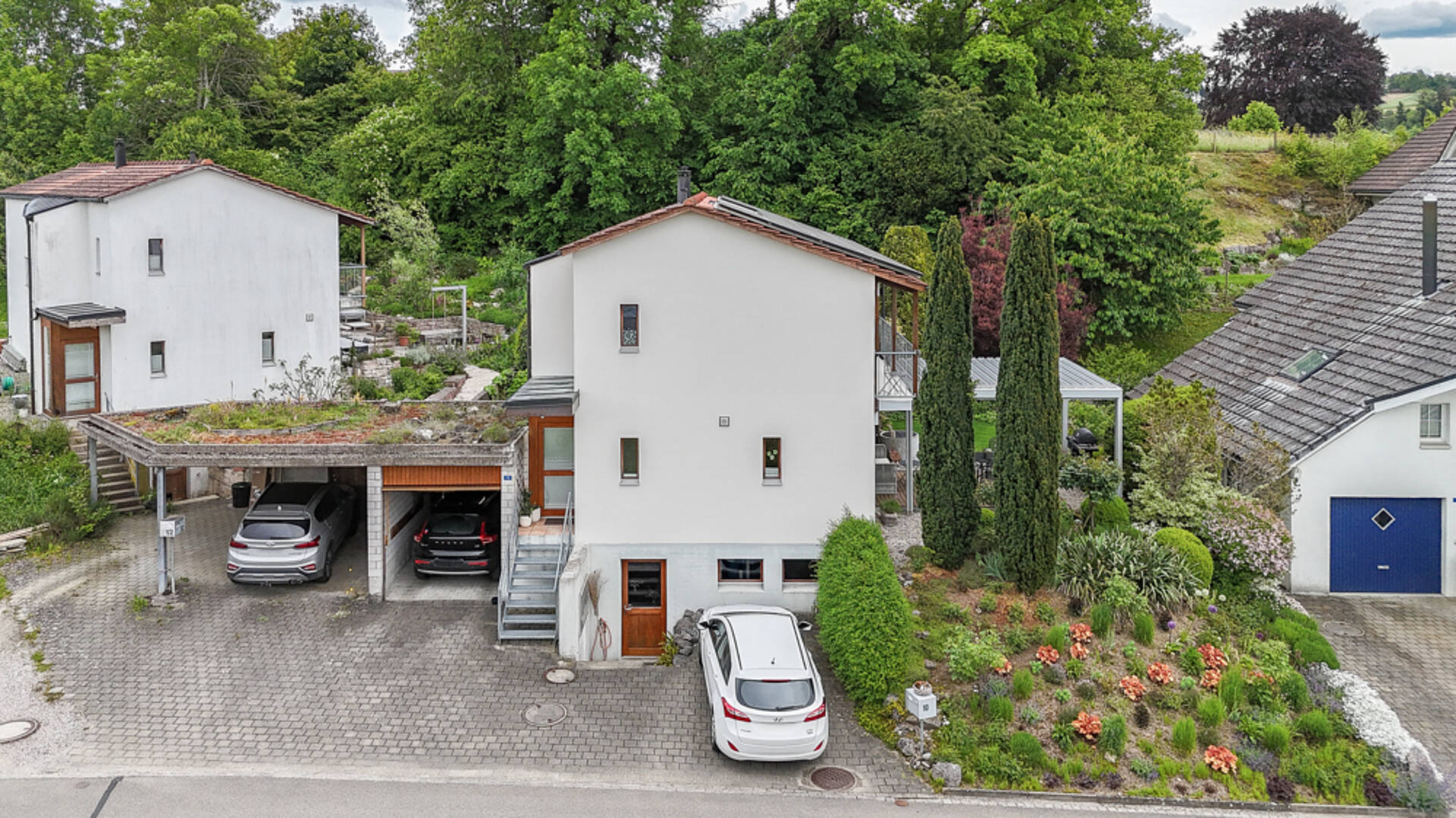 Außenansicht eines modernen Wohnhauses mit Garage und Gartenhang