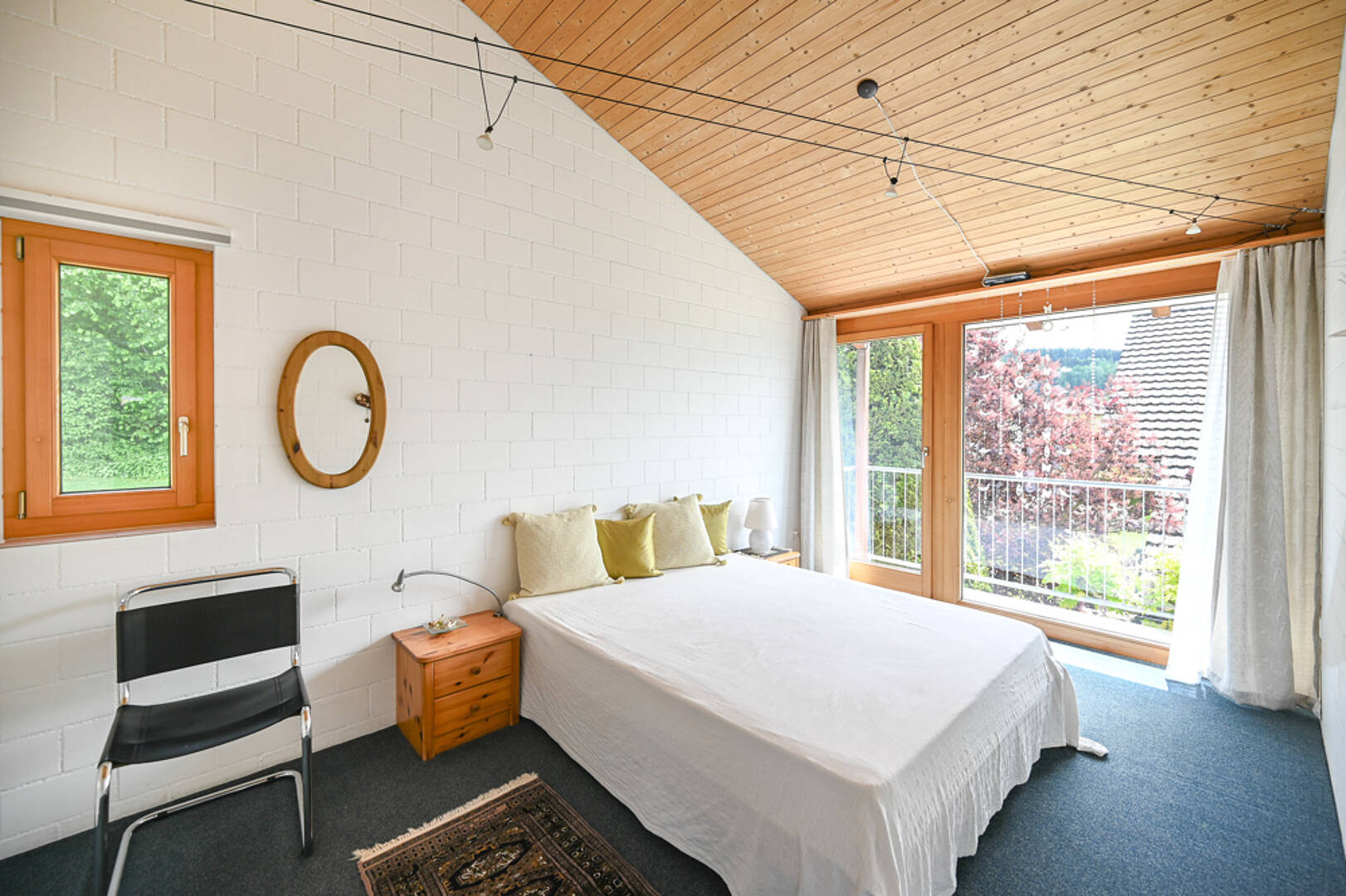 Helles Schlafzimmer mit Holzdecke und Balkonblick