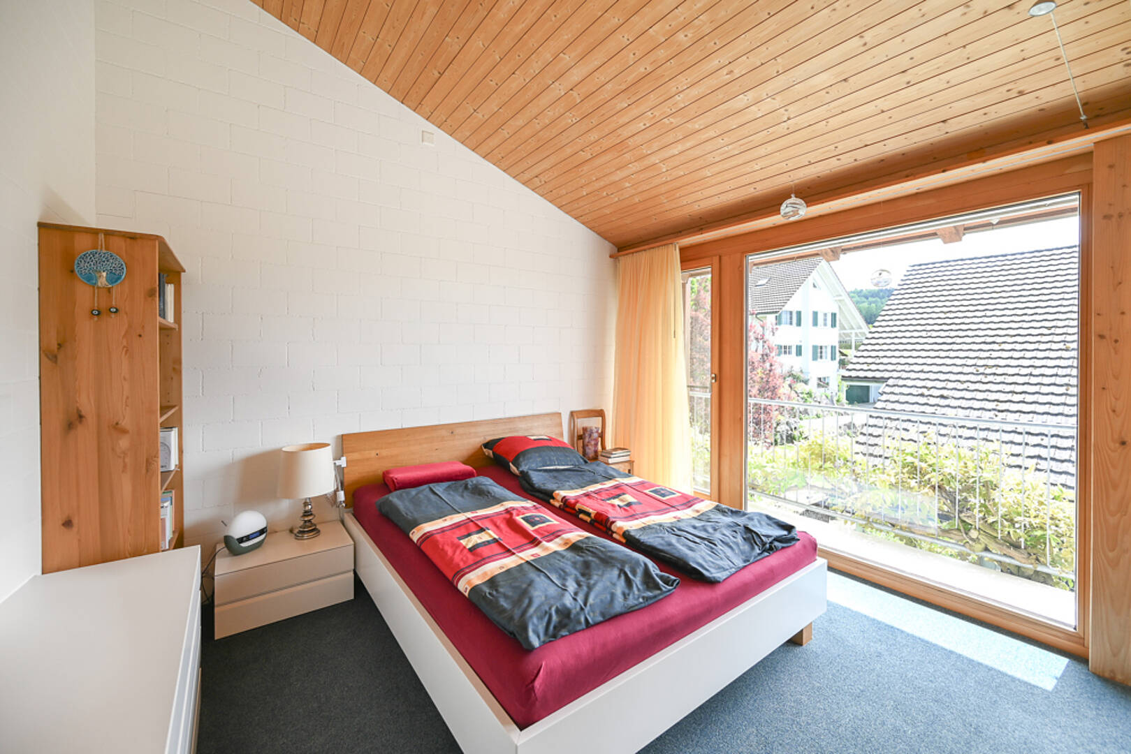 Helles Schlafzimmer mit Holzdecke und großem Fenster