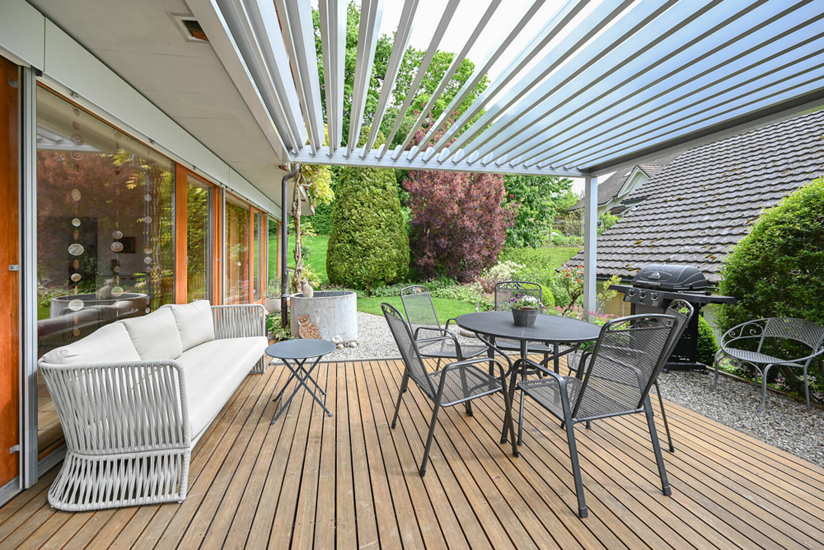 Überdachte Holzterrasse mit Gartenmöbeln
