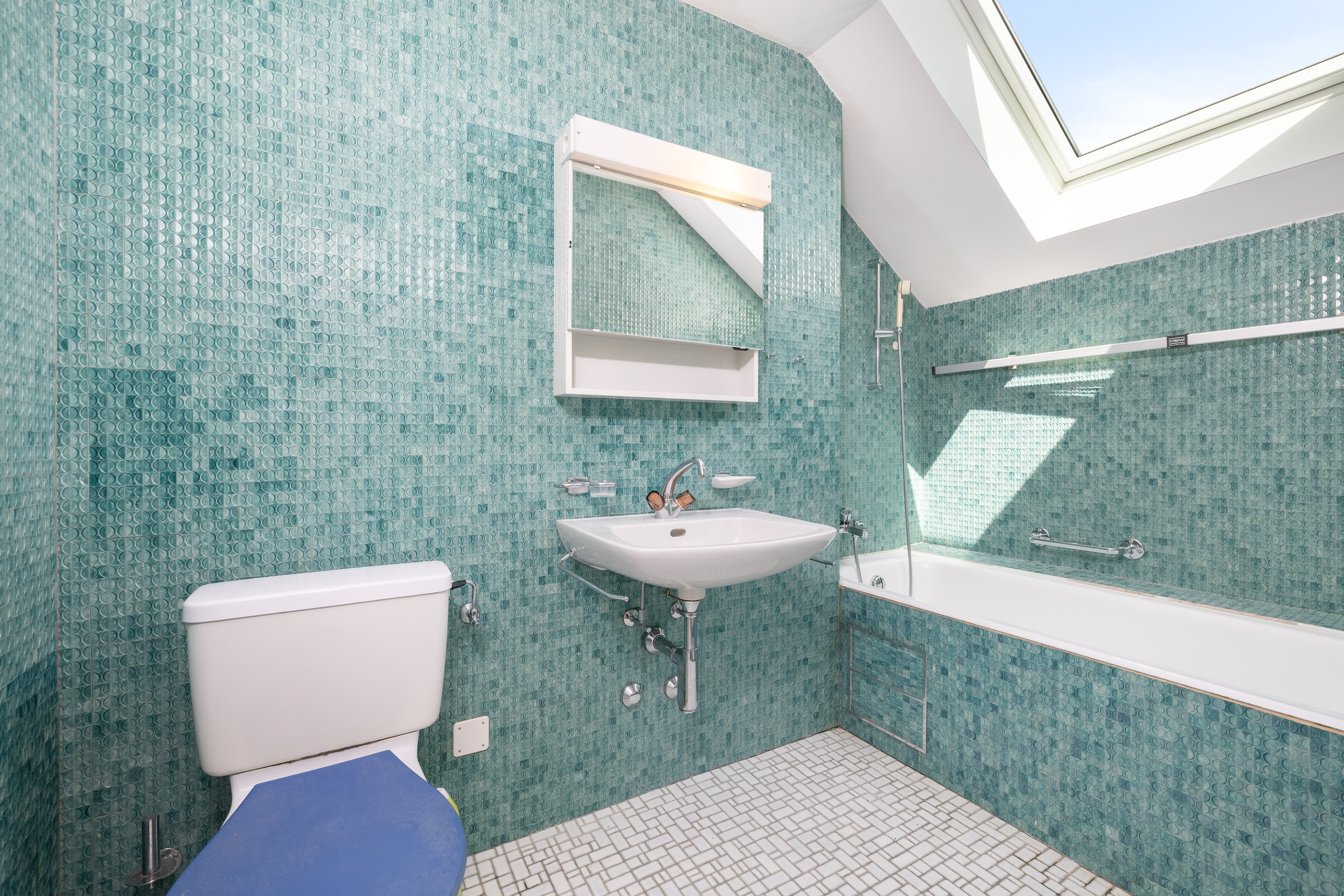 Badezimmer mit türkisfarbenen Fliesen und Dachfenster