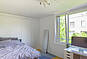 Helles Schlafzimmer mit großem Fenster und Blick ins Grüne