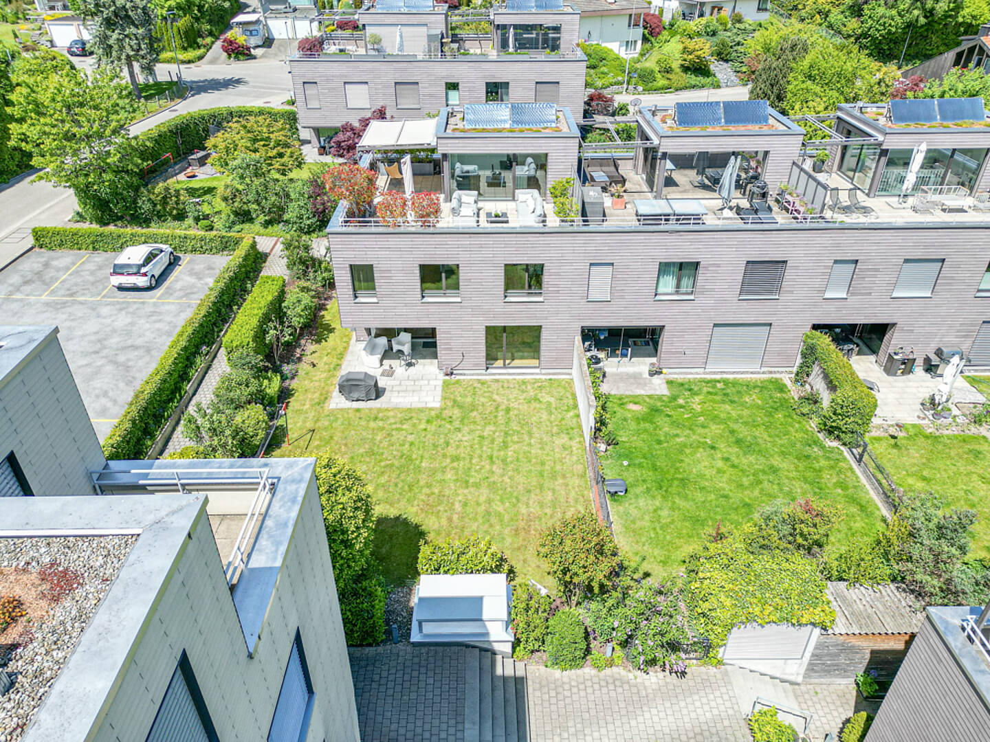 Drohnenaufnahme eines modernen Wohnensembles mit Dachterrassen und Gärten