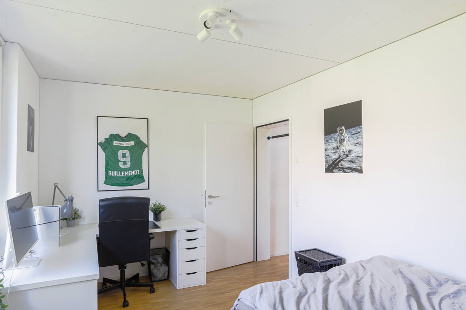Schlafzimmer mit Schreibtisch und Sportposter