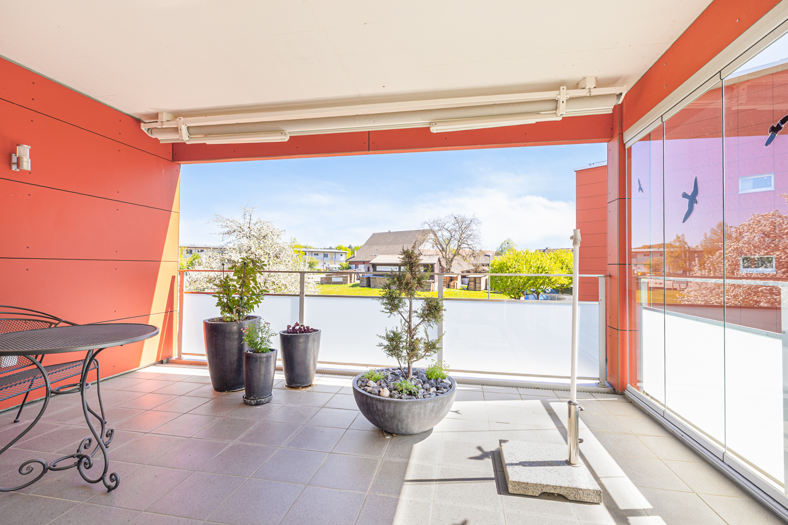 Überdachter Balkon mit Pflanzen und Blick ins Grüne