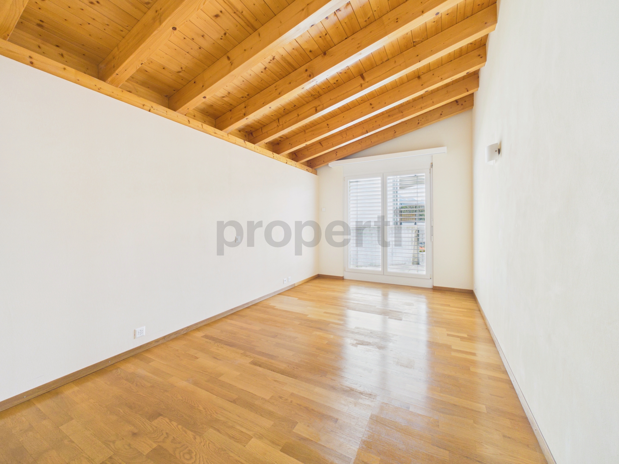 Leeres, helles Zimmer mit Holzbalkendecke