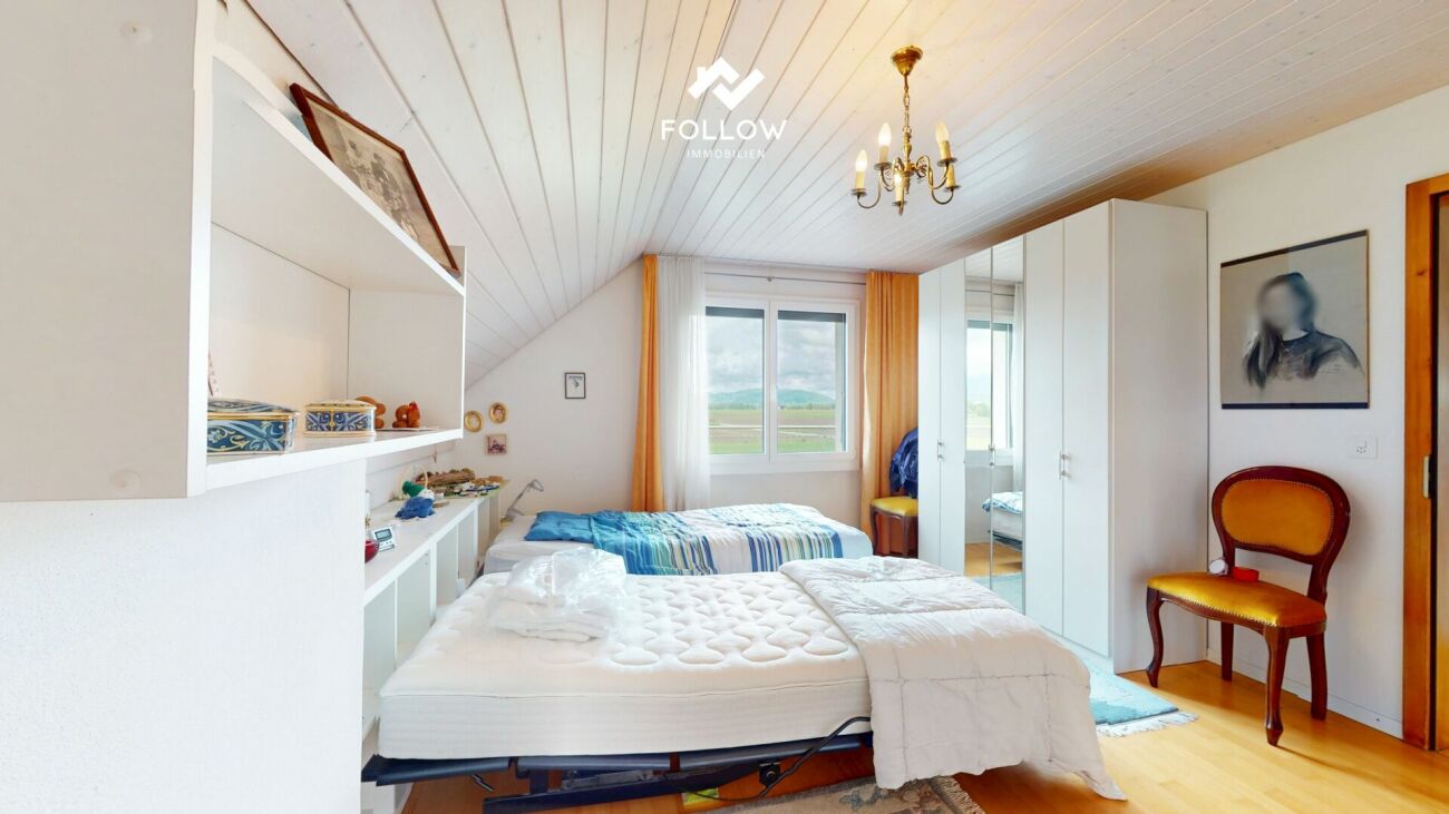 Helles Schlafzimmer mit Dachschräge und Blick ins Grüne