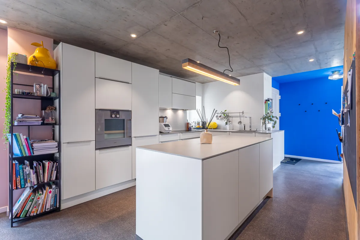 Moderne offene Küche mit Betonoptik und kräftiger blauer Akzentwand