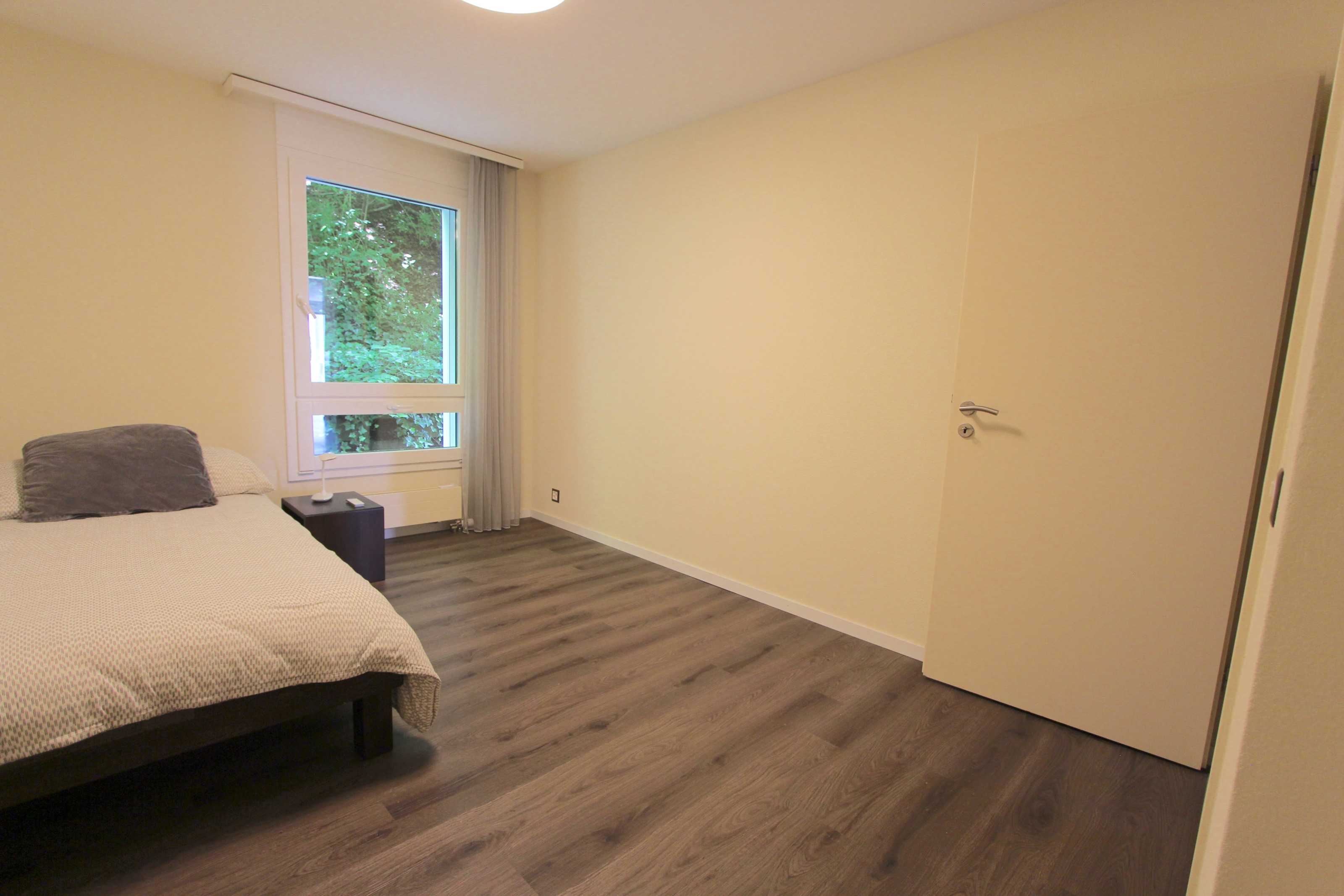 Schlichtes Schlafzimmer mit Blick ins Grüne