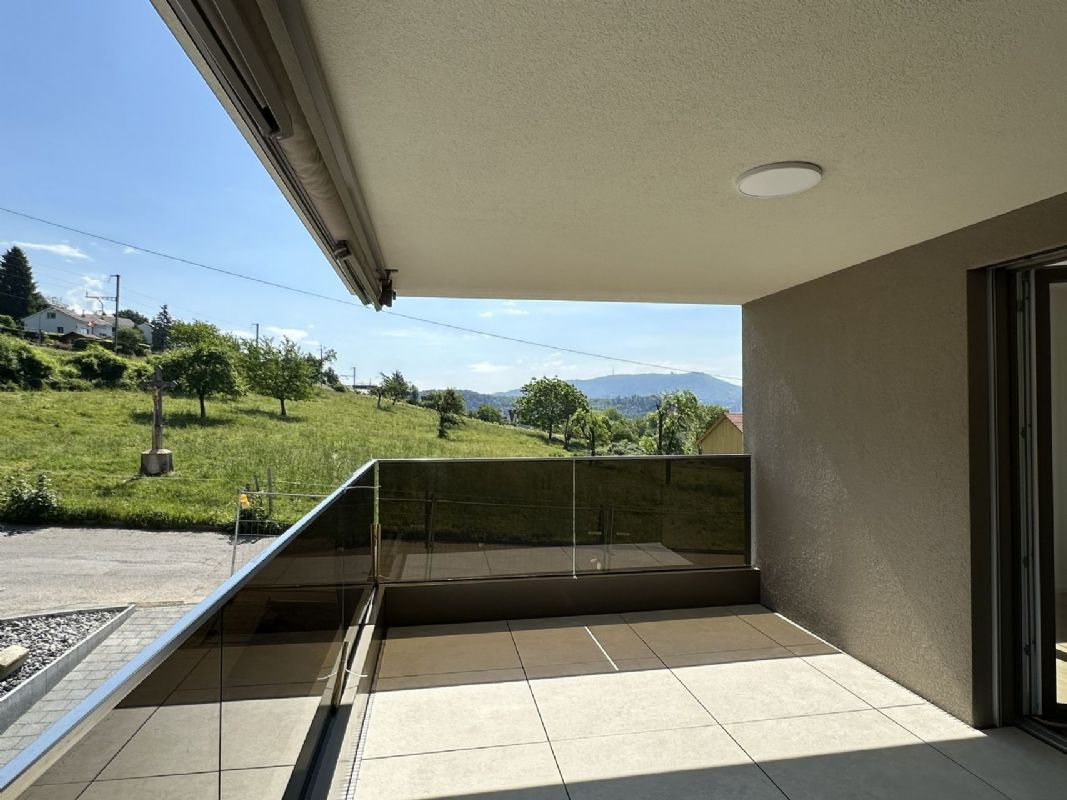 Überdachter Balkon mit Glasgeländer und Bergblick