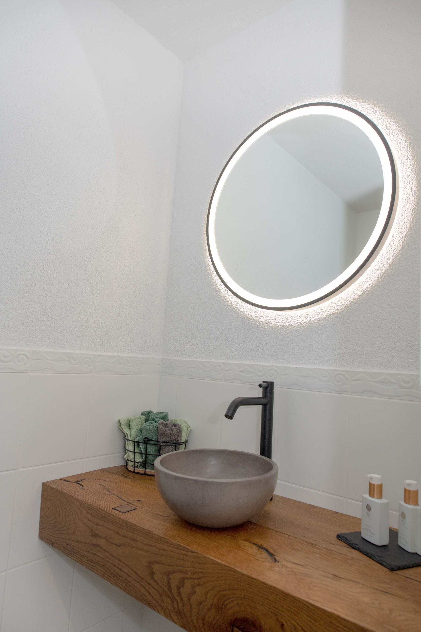 Modernes Gäste-WC mit beleuchtetem Rundspiegel