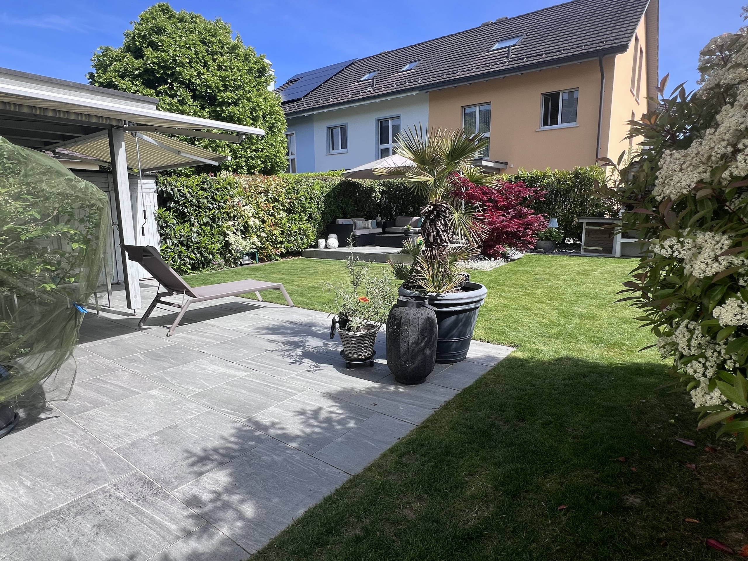 Gepflegter Garten mit Terrasse vor einem Mehrfamilienhaus