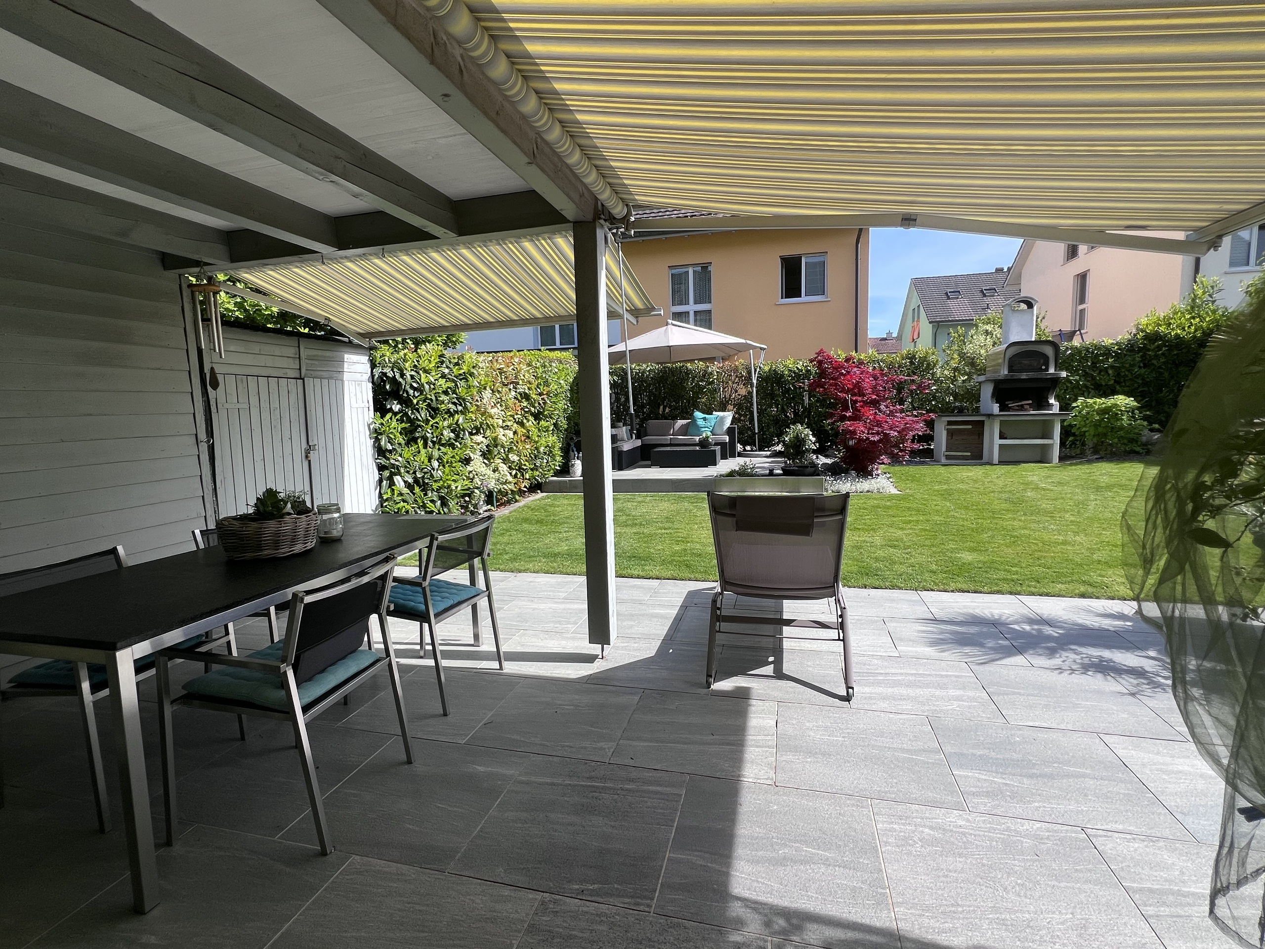 Überdachte Terrasse mit Gartenmöbeln und Außenküche