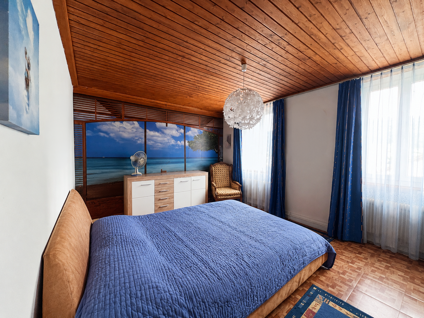 Schlafzimmer mit Holzdecke und Meerwandbild