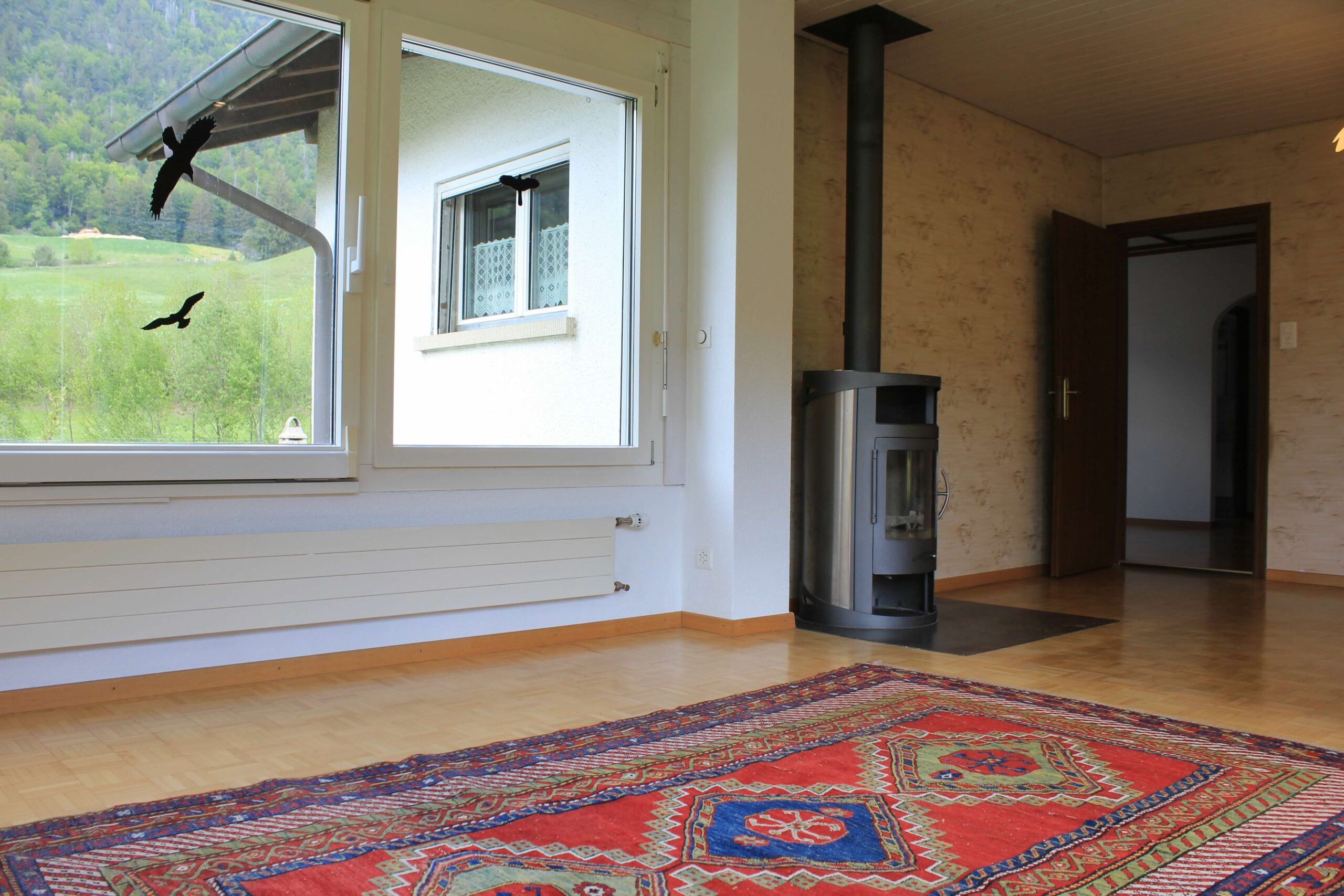 Helles Wohnzimmer mit Holzofen und Bergblick