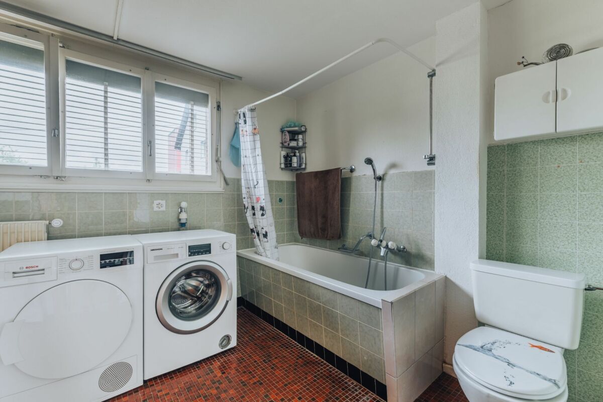Badezimmer mit Waschmaschine und Badewanne