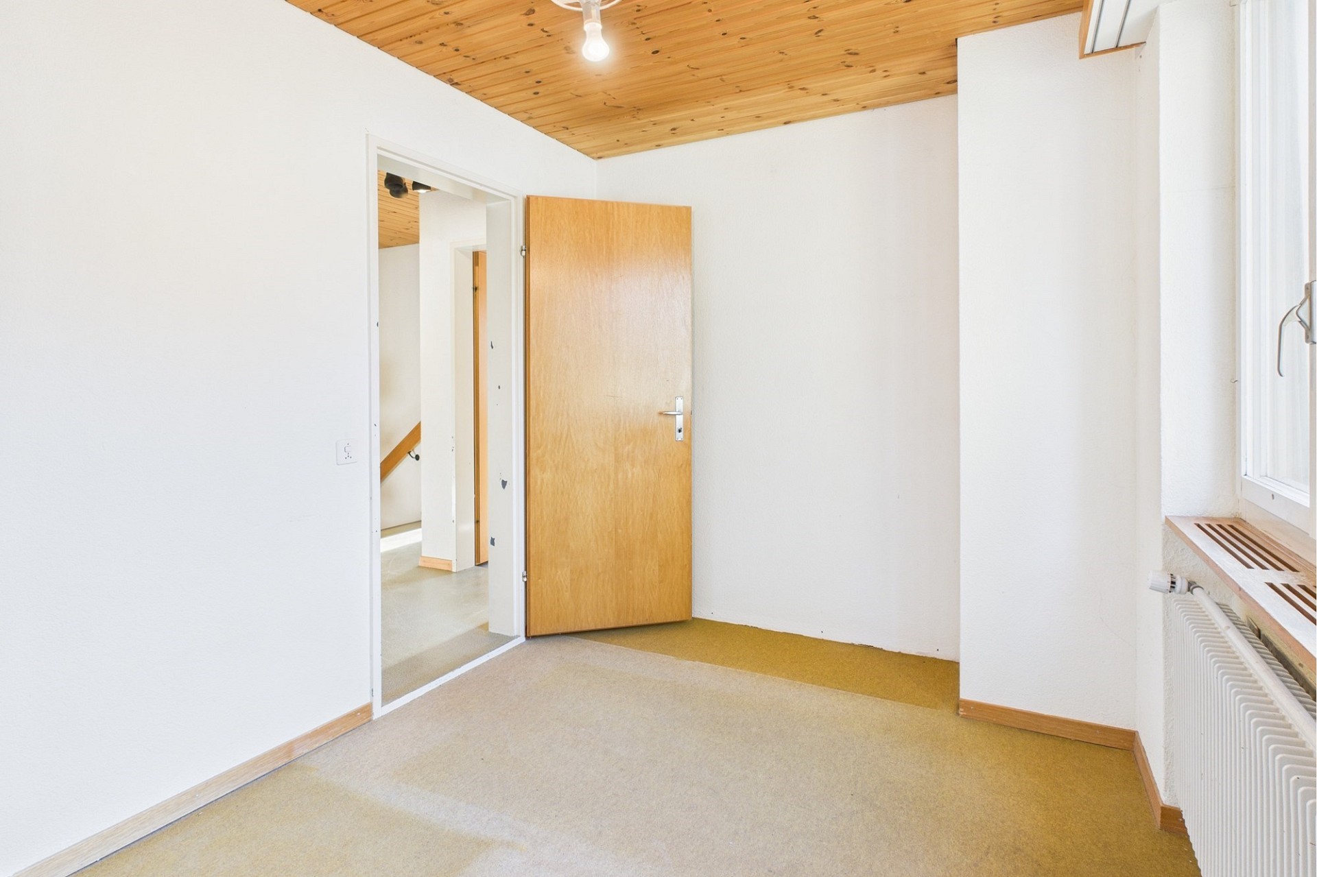 Heller Raum mit Holztür und Dachschräge