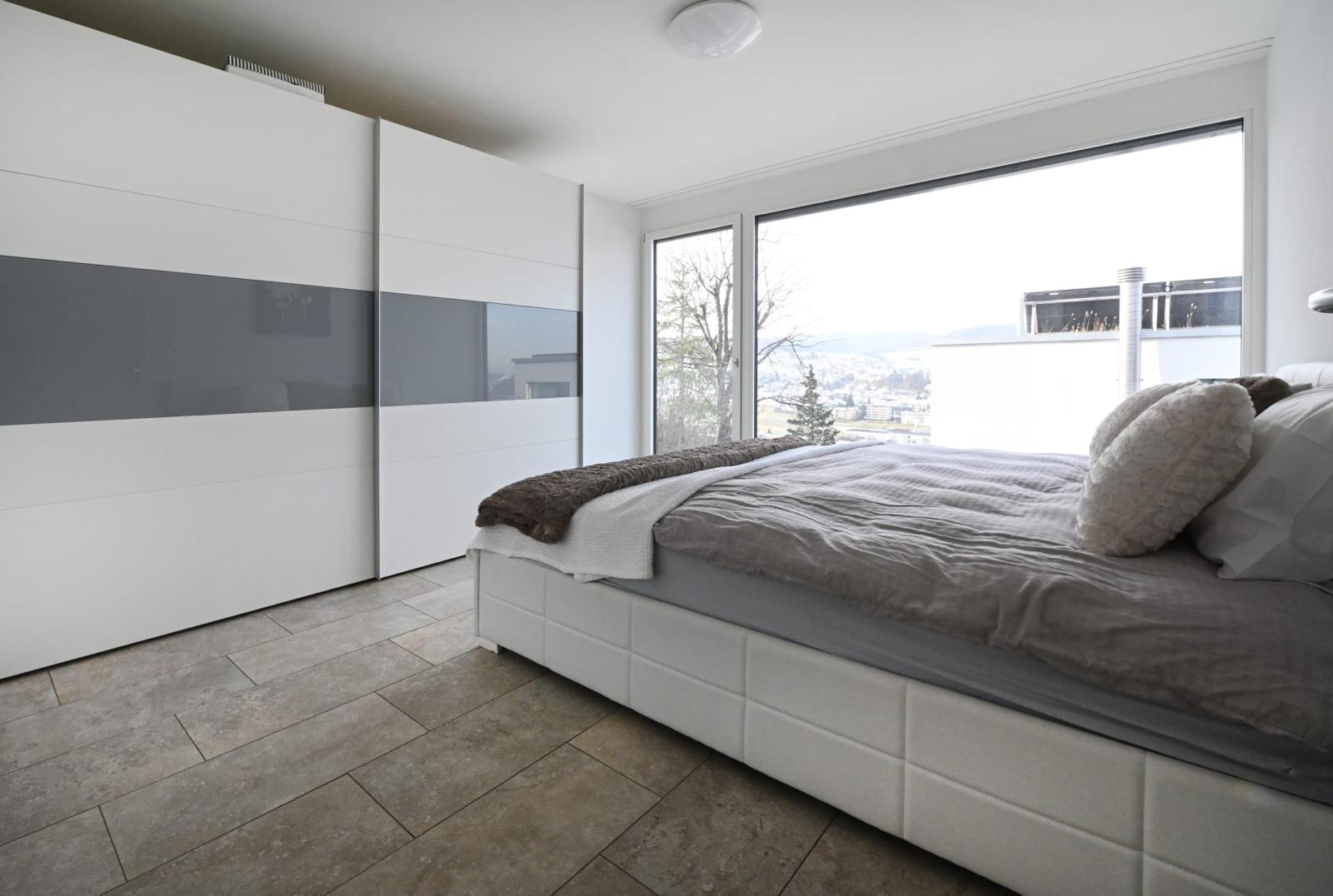Helles Schlafzimmer mit großem Fenster und Einbauschrank