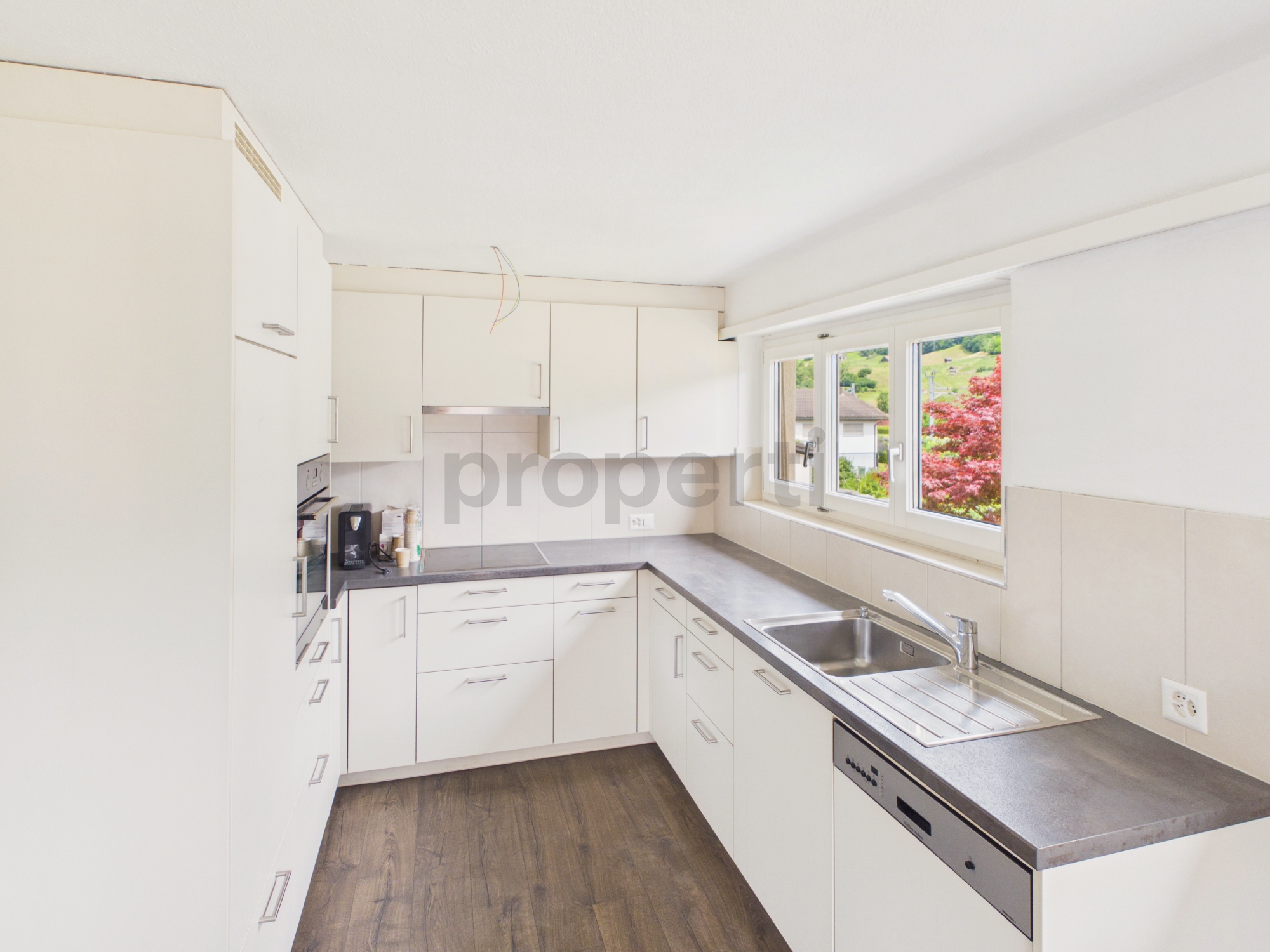Moderne weiße Einbauküche mit Fensterblick