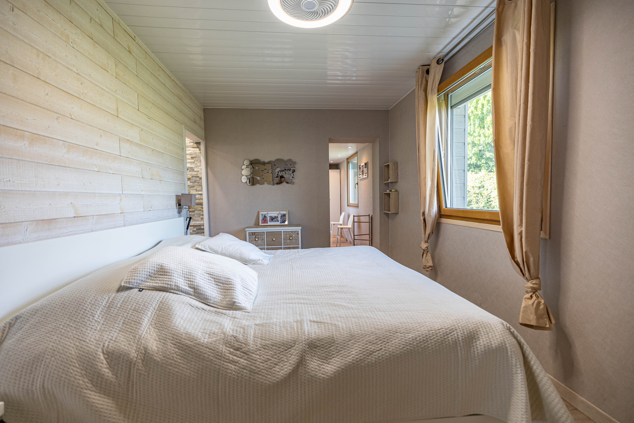 Helles Schlafzimmer mit Holzverkleidung und großem Fenster