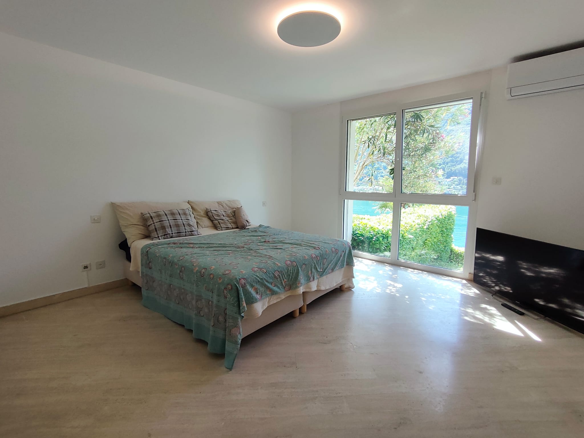 Helles Schlafzimmer mit großem Fenster und Seeblick