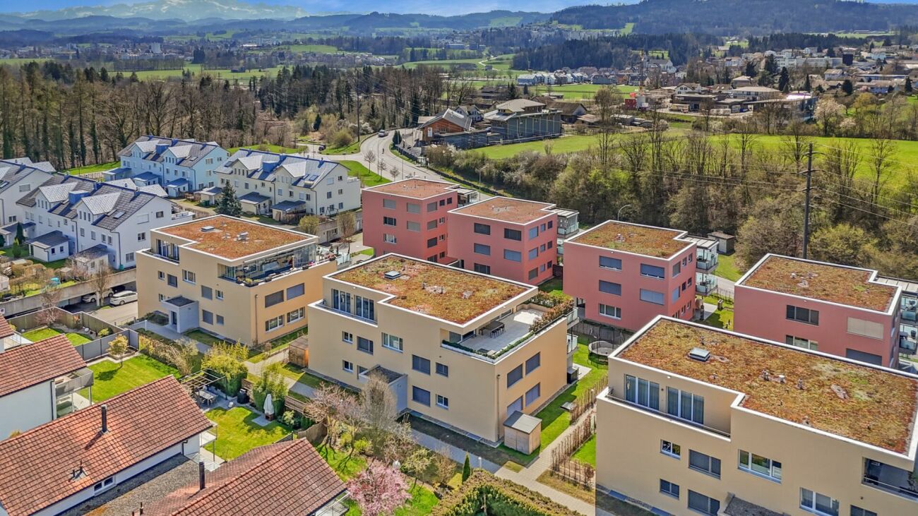 Luftaufnahme einer Wohnsiedlung mit Flachdachgebäuden und Bergblick