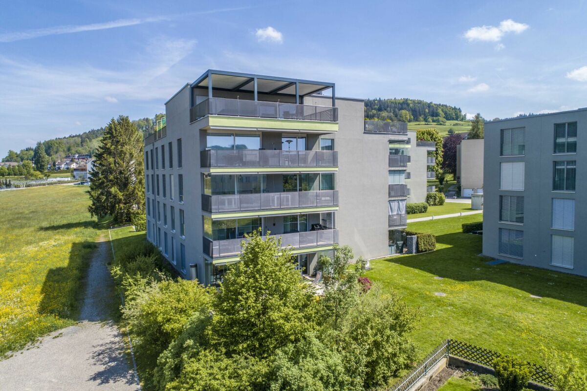 Modernes Mehrfamilienhaus mit Balkonen in grüner Umgebung