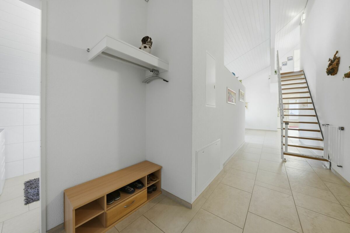 Heller Eingangsbereich mit Treppe und Garderoben­nische