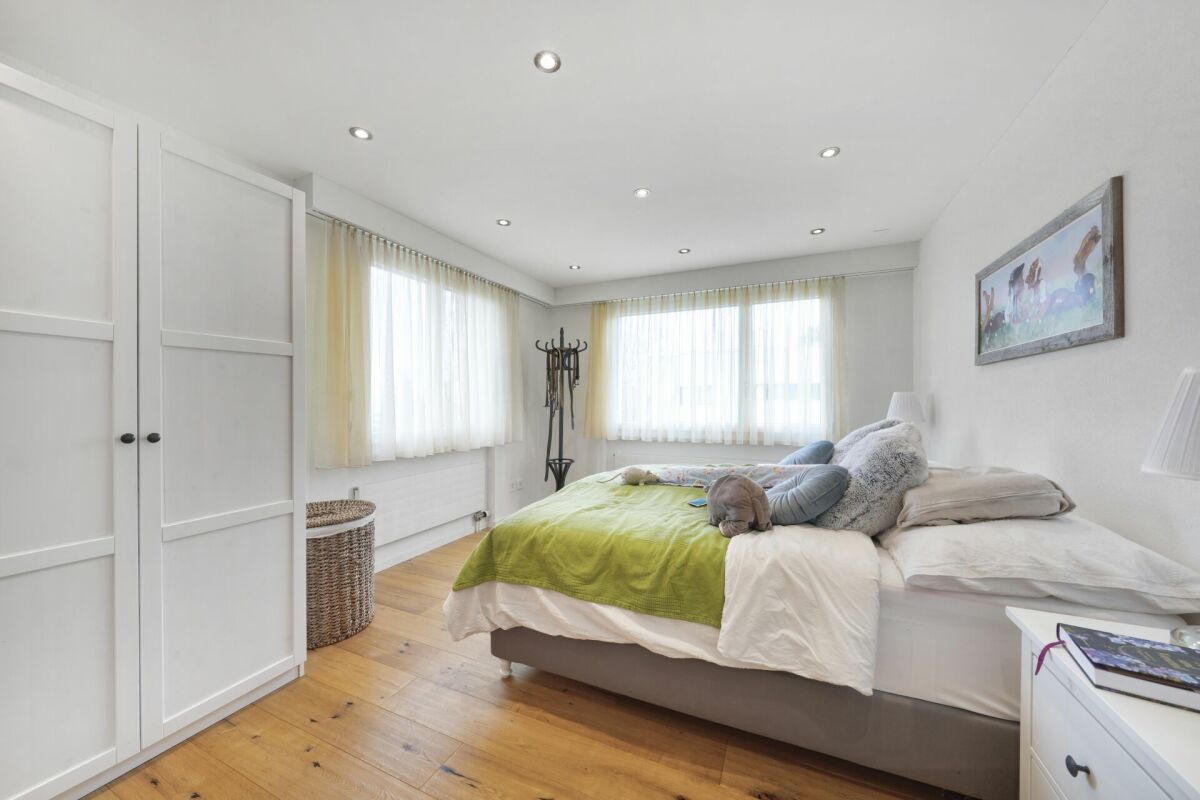 Helles Schlafzimmer mit Doppelbett und großen Fenstern