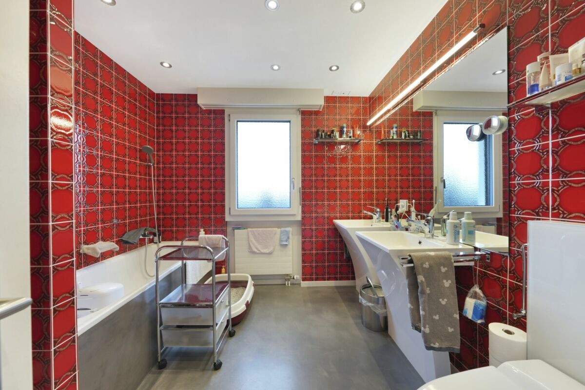 Bunt gefliestes Badezimmer mit Badewanne und Doppelwaschtisch