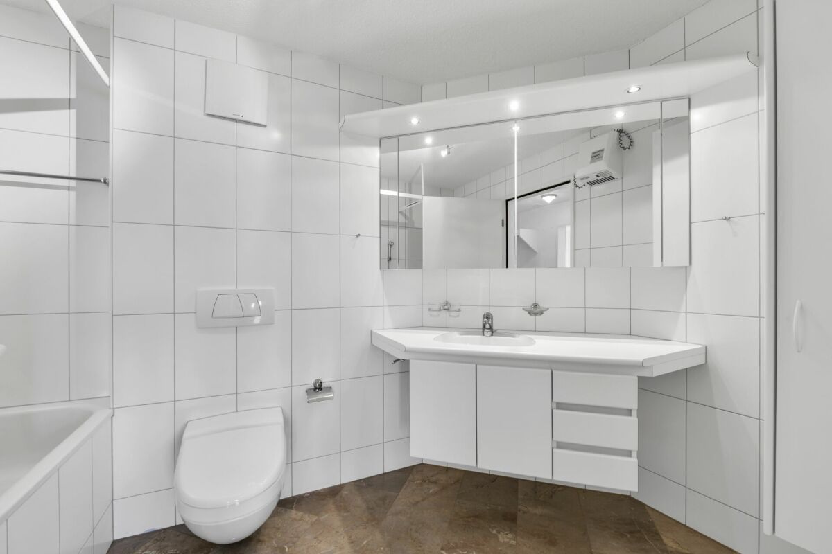 Modernes Badezimmer mit weißen Fliesen und großer Spiegelfront
